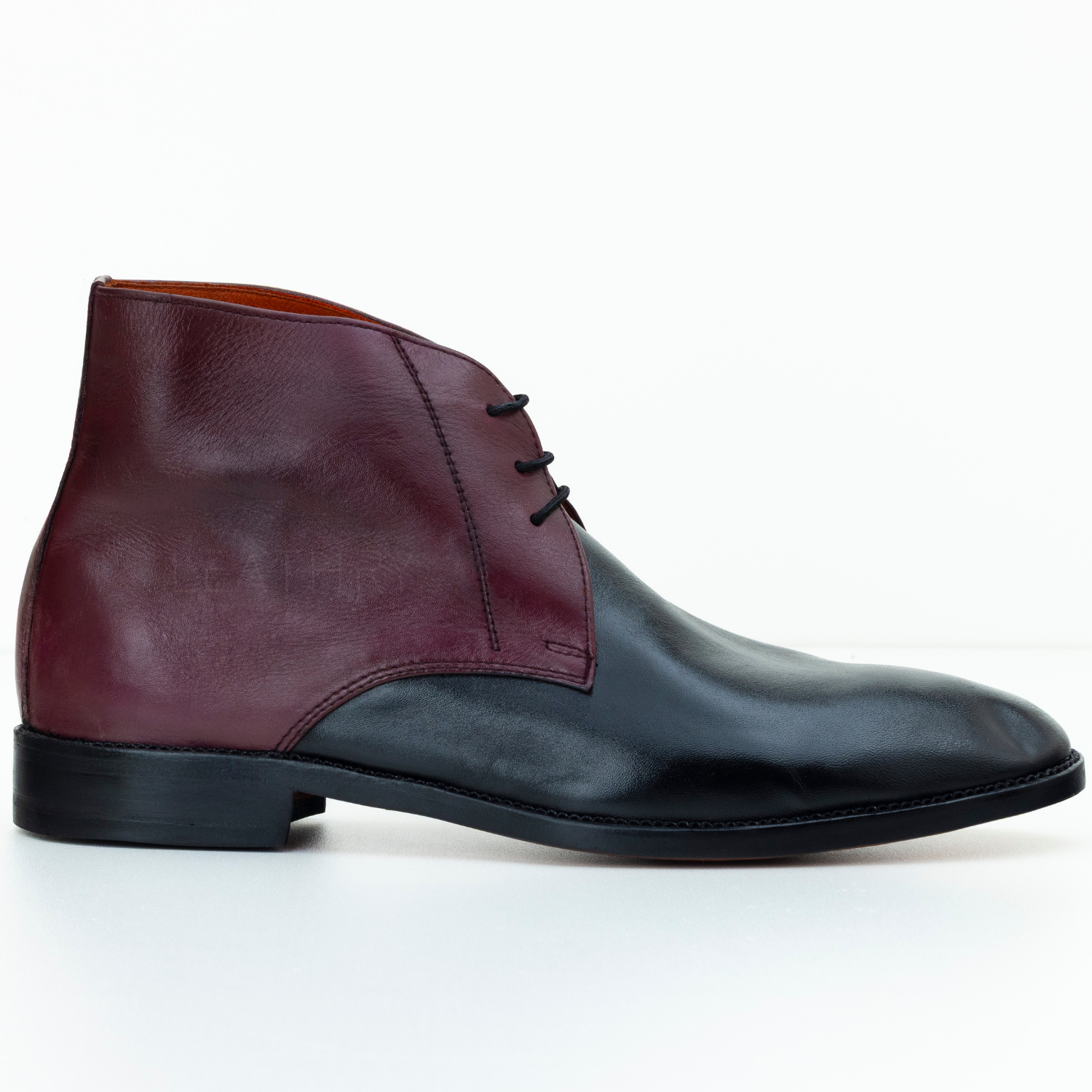 Two-tone leather shoe with maroon upper and black sole on a white background
