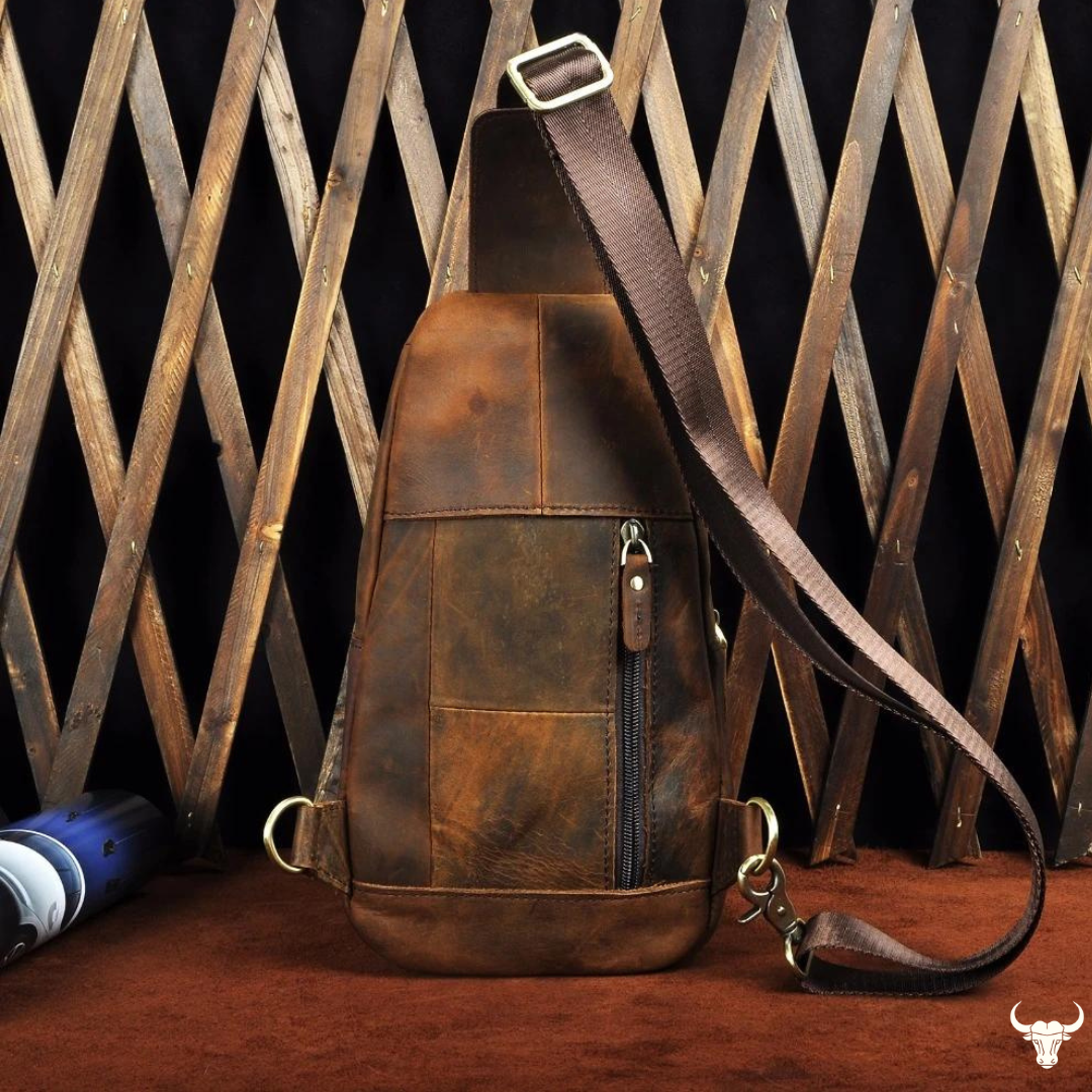 Brown leather sling bag on a wooden surface with a rustic background