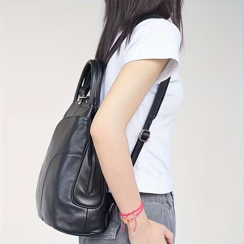 Person holding a black leather handbag against a plain background