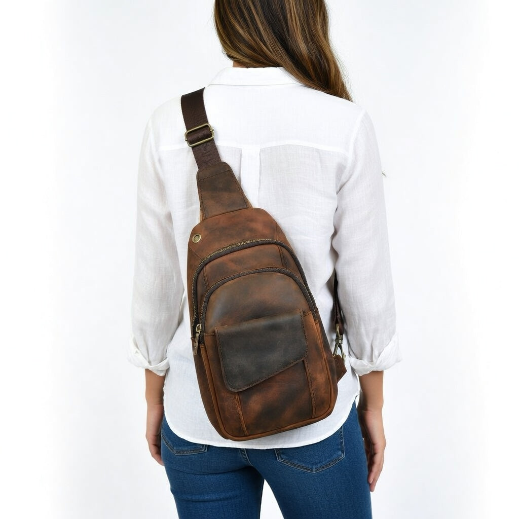 Person wearing a brown leather sling bag on a white background