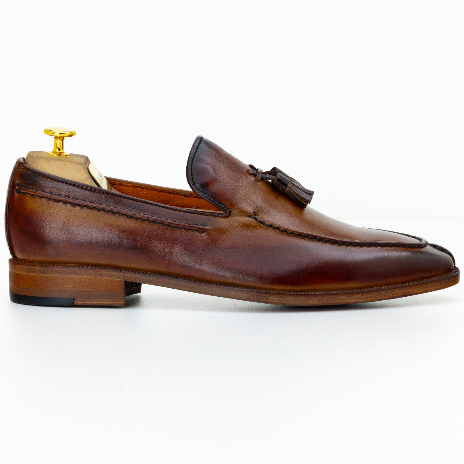Brown leather loafer with a tassel on a white background