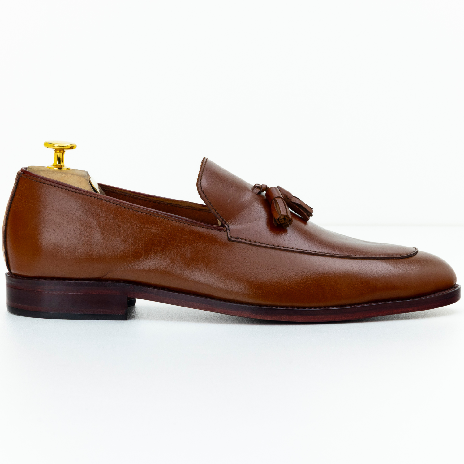 Brown leather loafer with a tassel on a white background