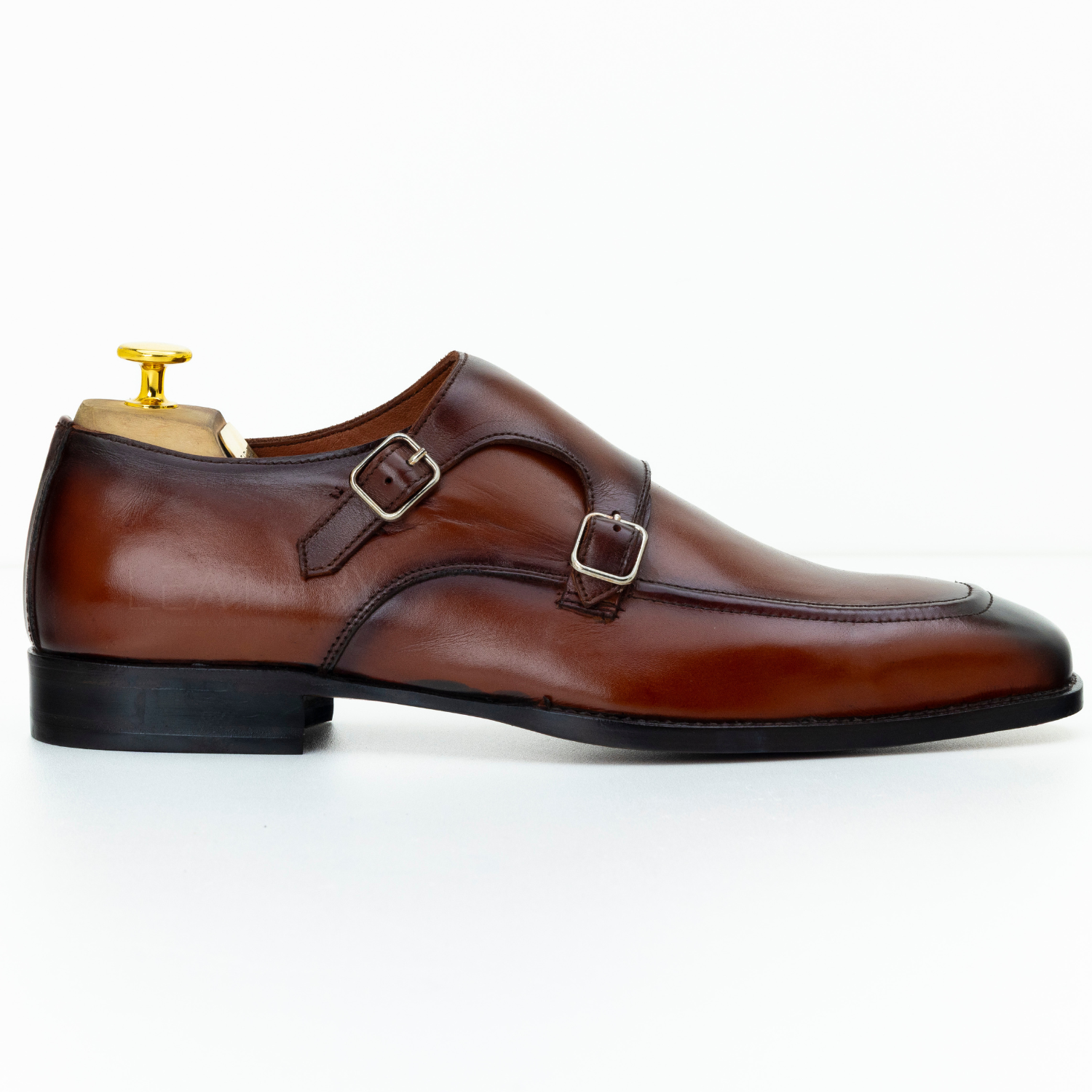 Brown leather shoe with gold buckle on a white background