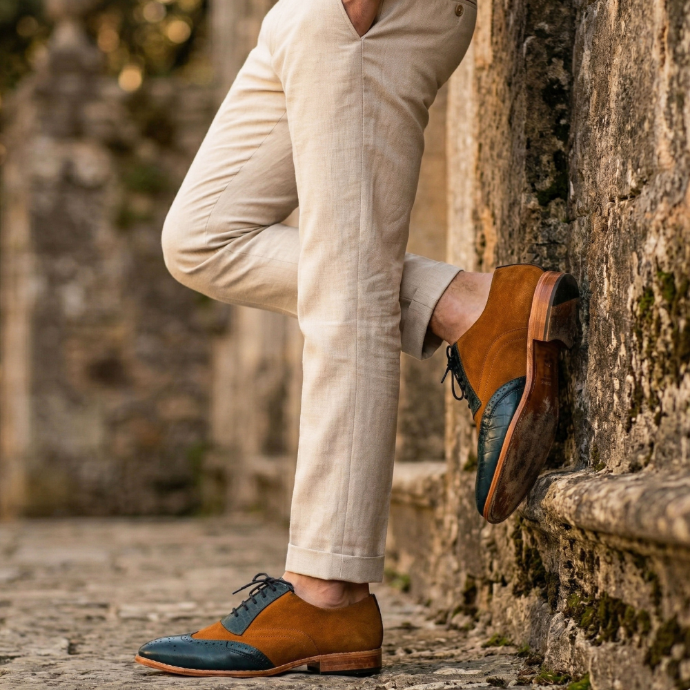 Person wearing brown shoes with blue soles against a stone wall.