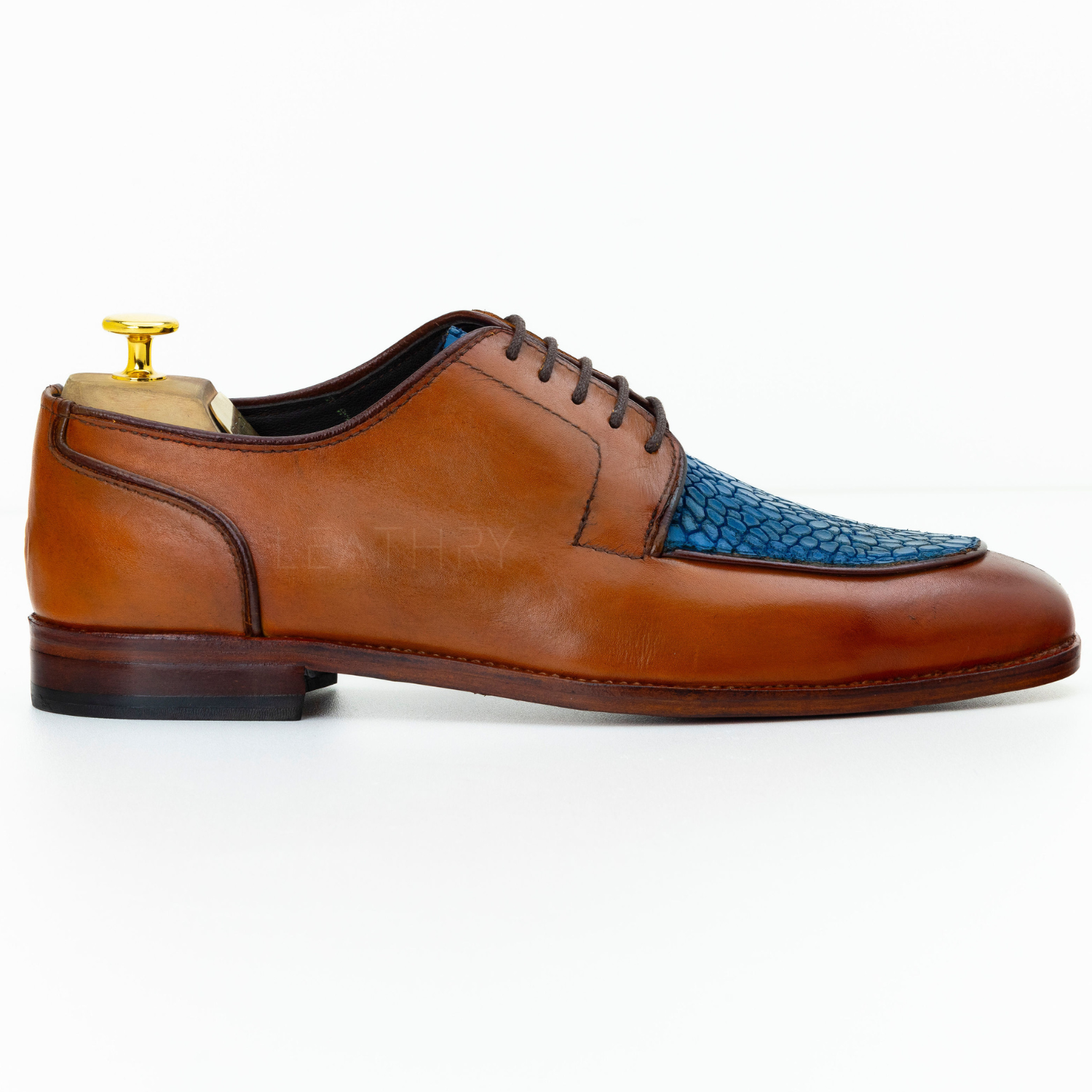 Brown leather dress shoe with blue textured toe cap on a white background