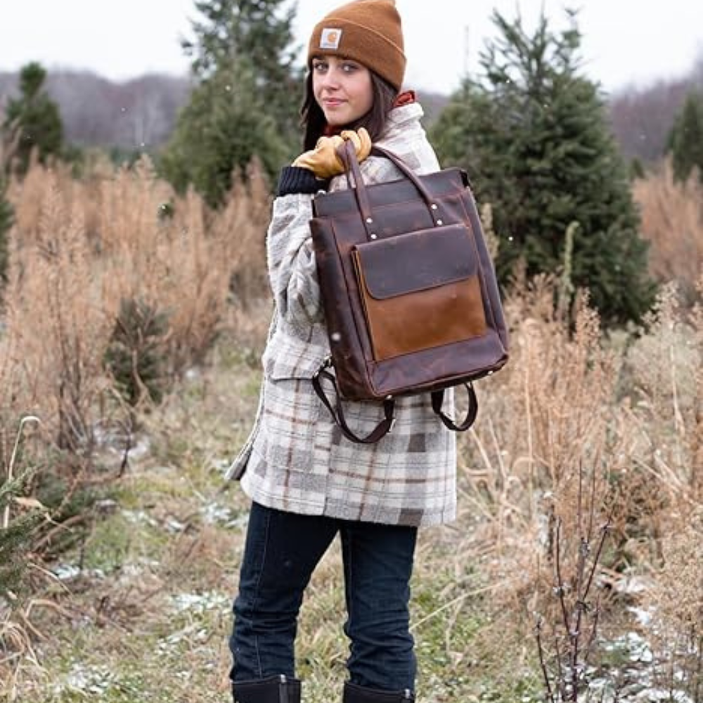 Person holding a brown leather backpack in a forest setting