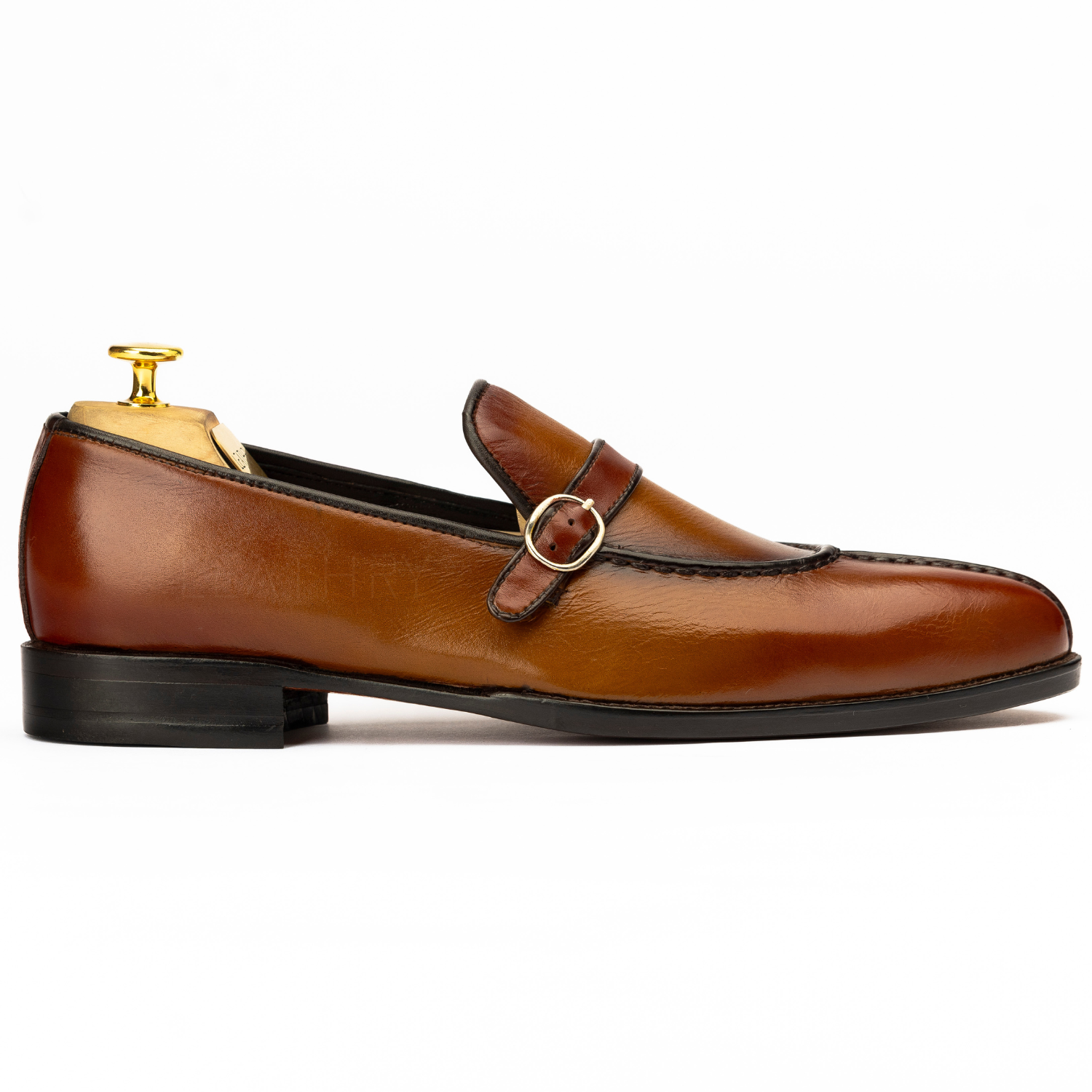 Brown leather loafer with a gold buckle on a white background