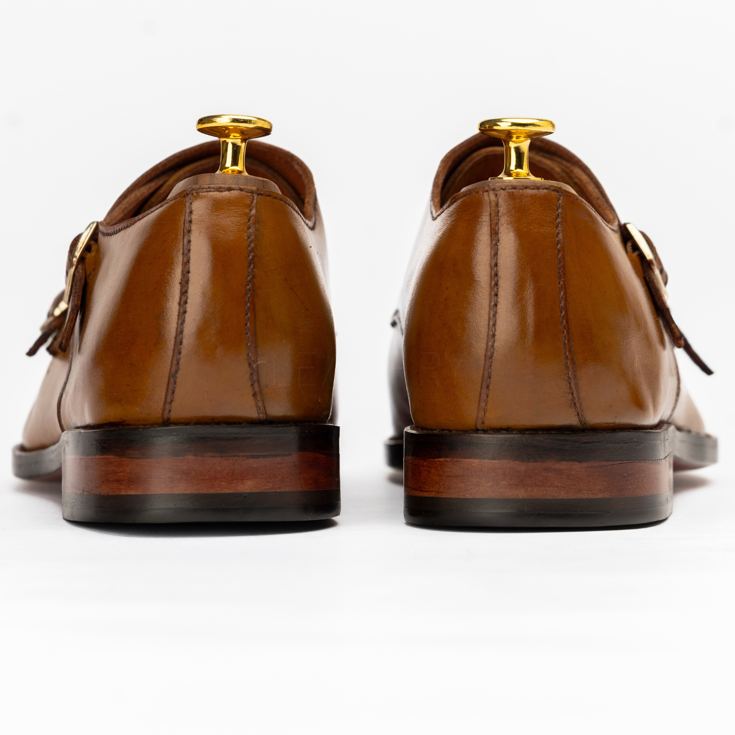 Brown leather shoes with gold buckles on a white background