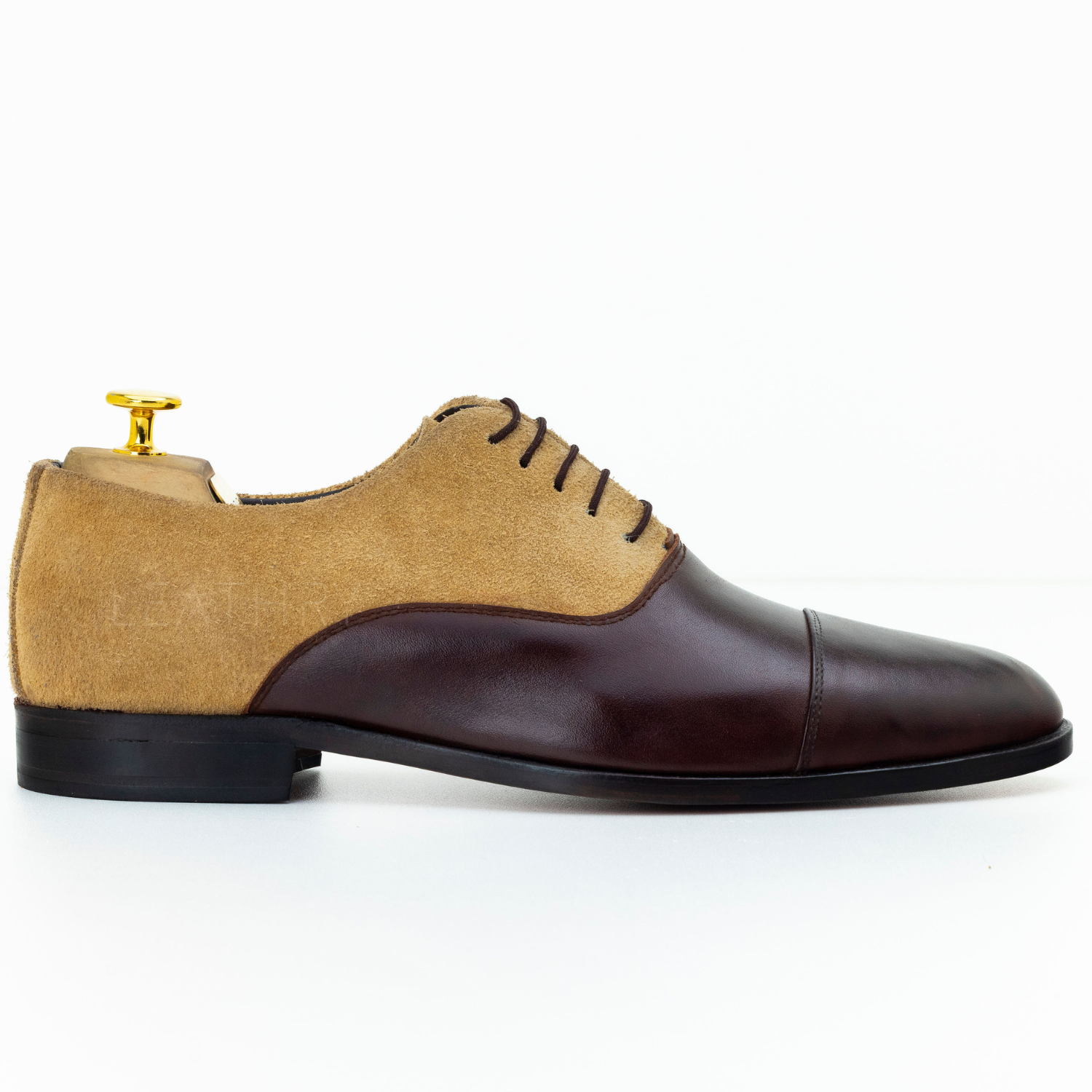 Brown and beige dress shoe with a gold buckle on a white background
