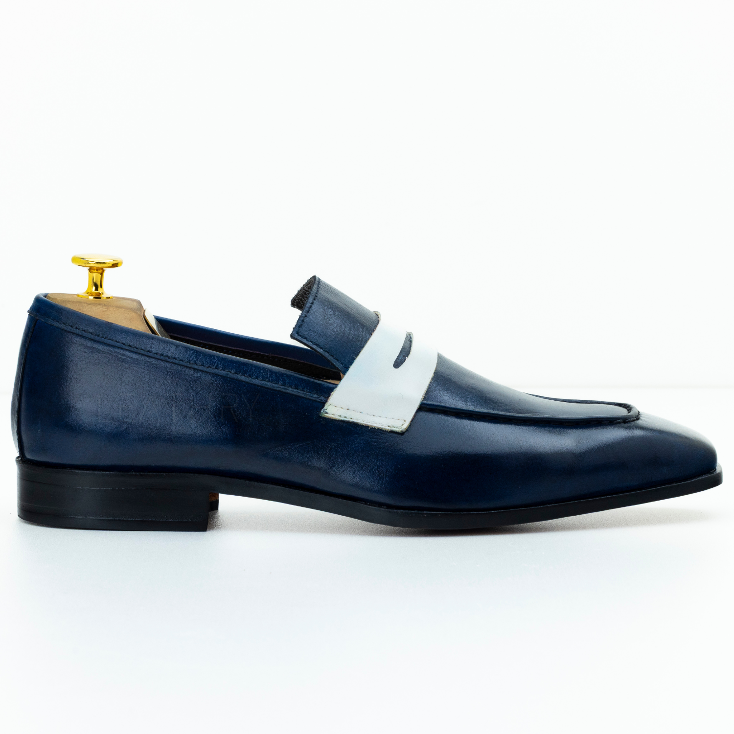 Blue loafer shoe with a white strap on a white background