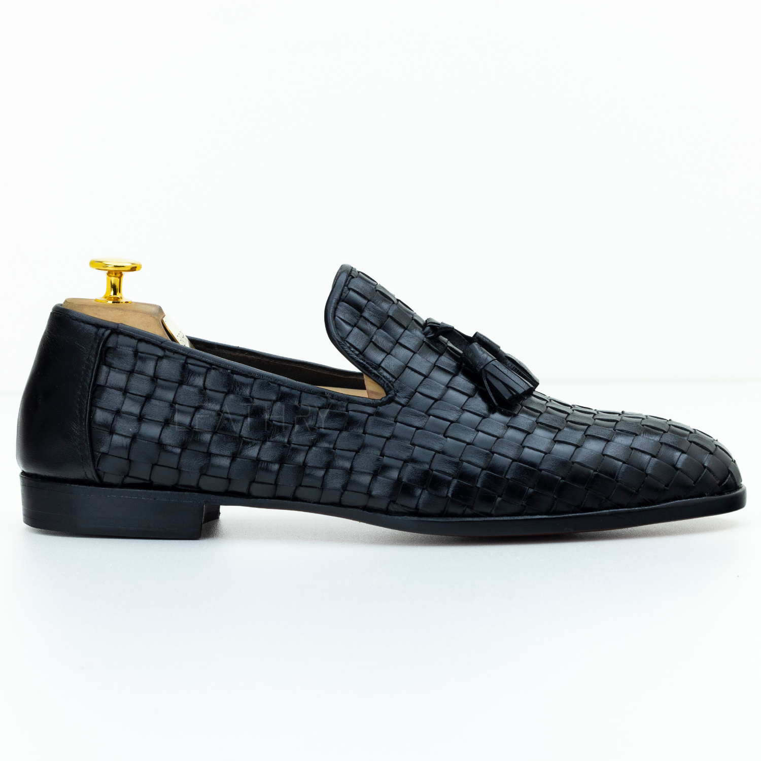 Black woven loafer with a gold buckle on a white background