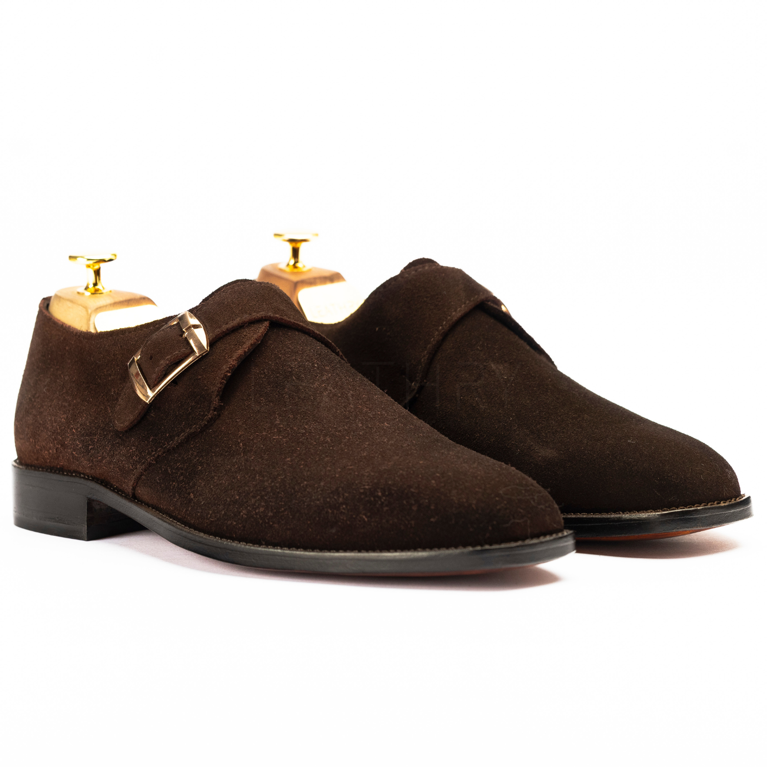 Pair of brown suede shoes with gold buckles on a white background