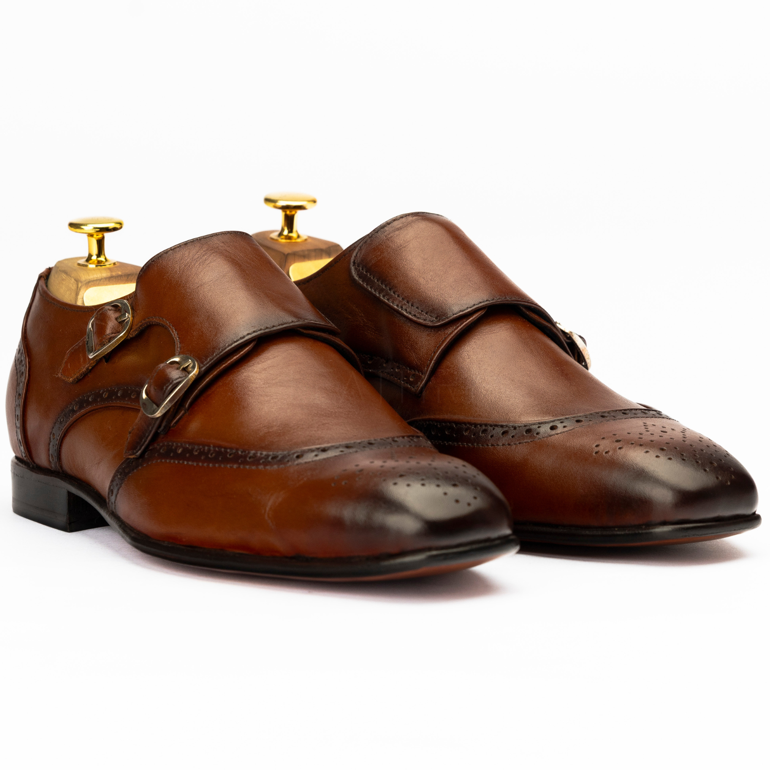 Pair of brown leather shoes with gold buckles on a white background