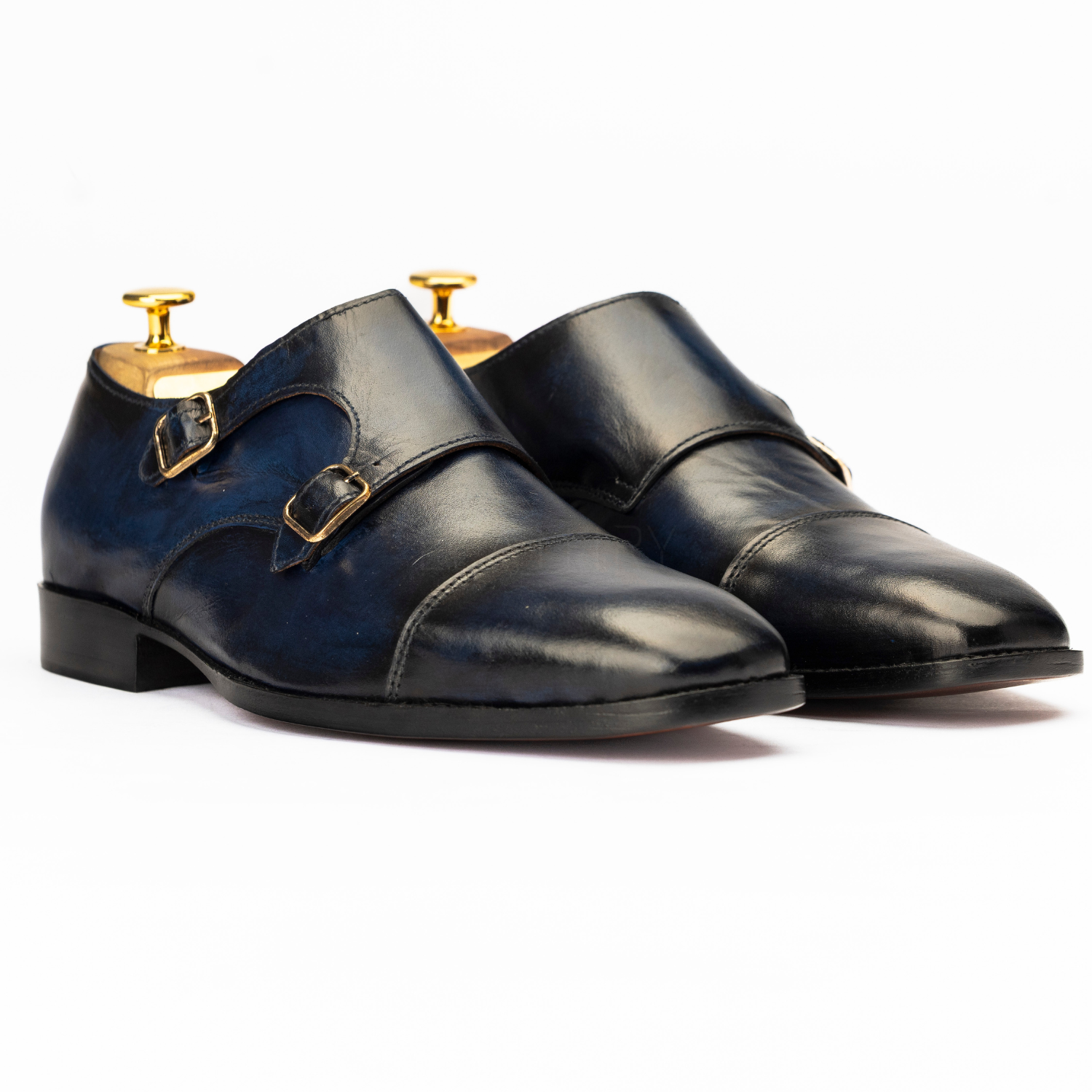 Pair of black leather shoes with gold buckles on a white background