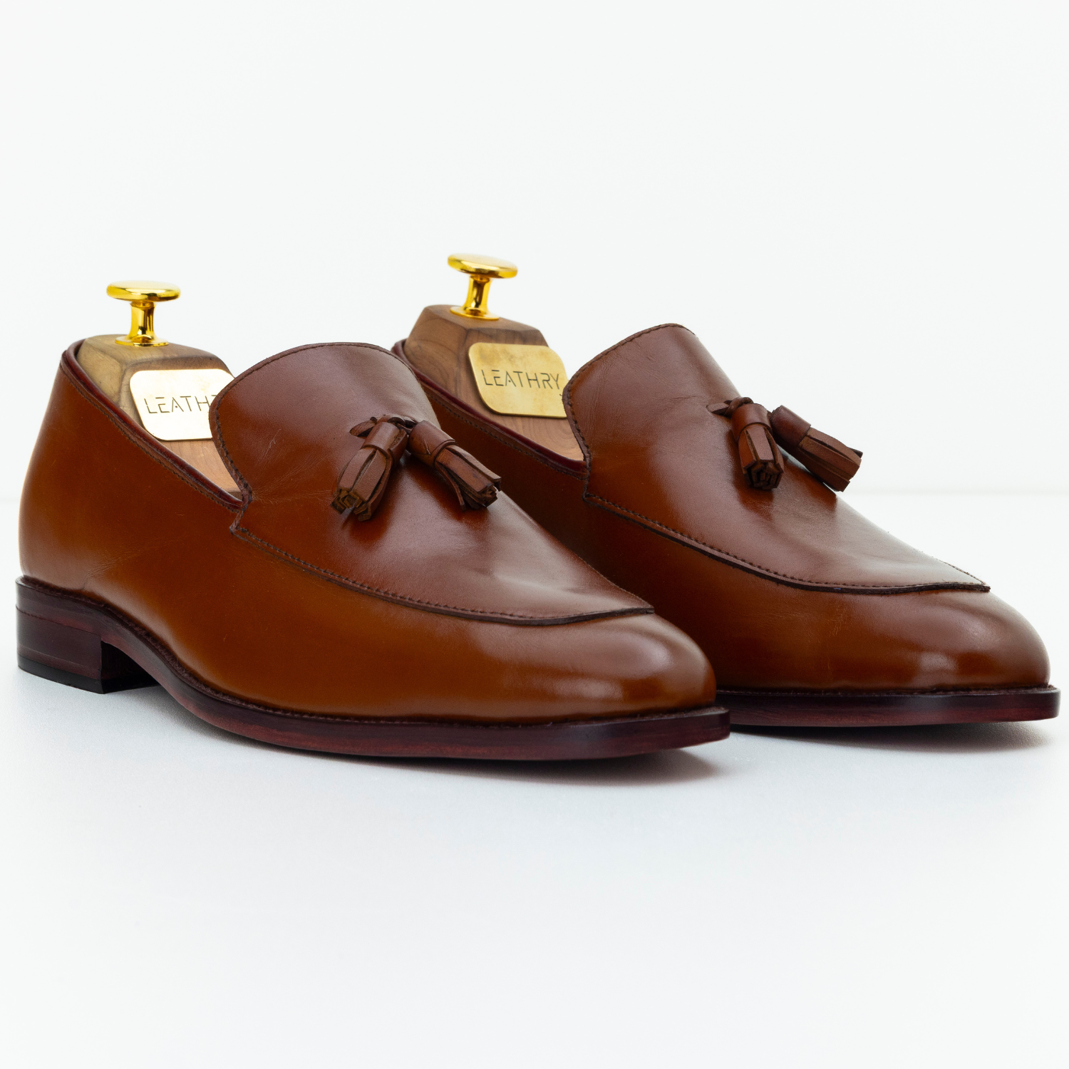 Pair of brown leather loafers with tassels on a white background