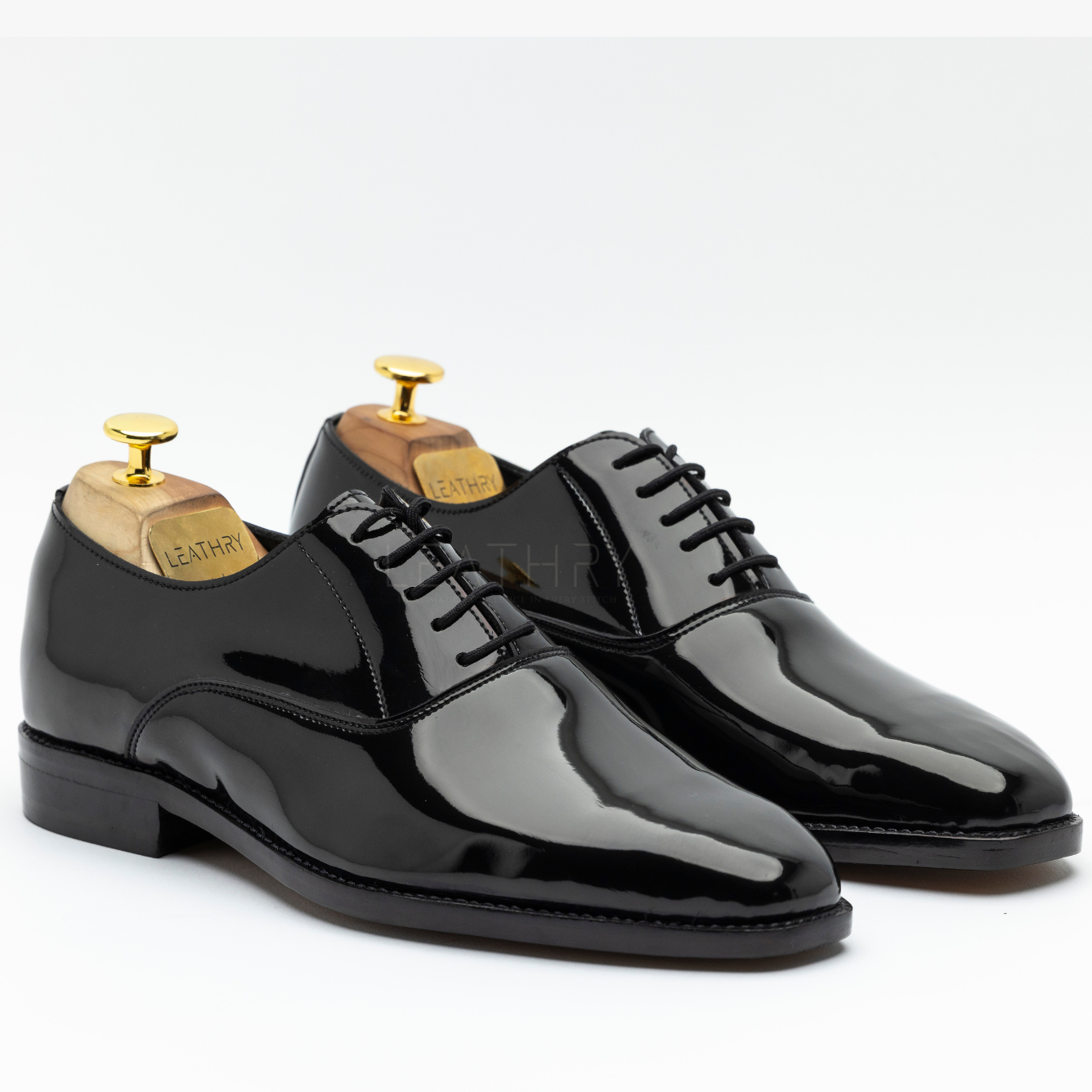 Pair of black patent leather shoes on a white background