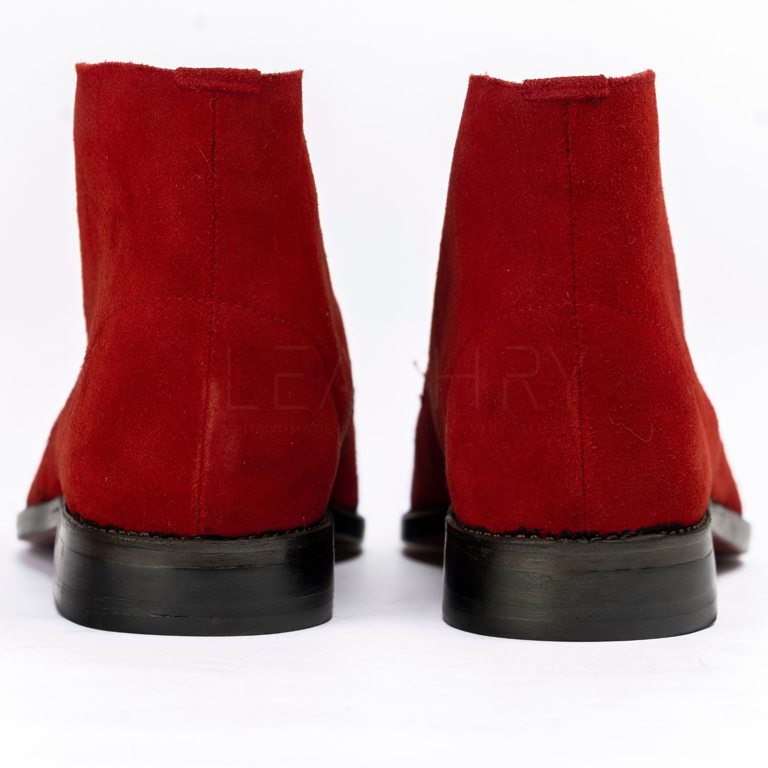 Red suede boots with black soles on a white background
