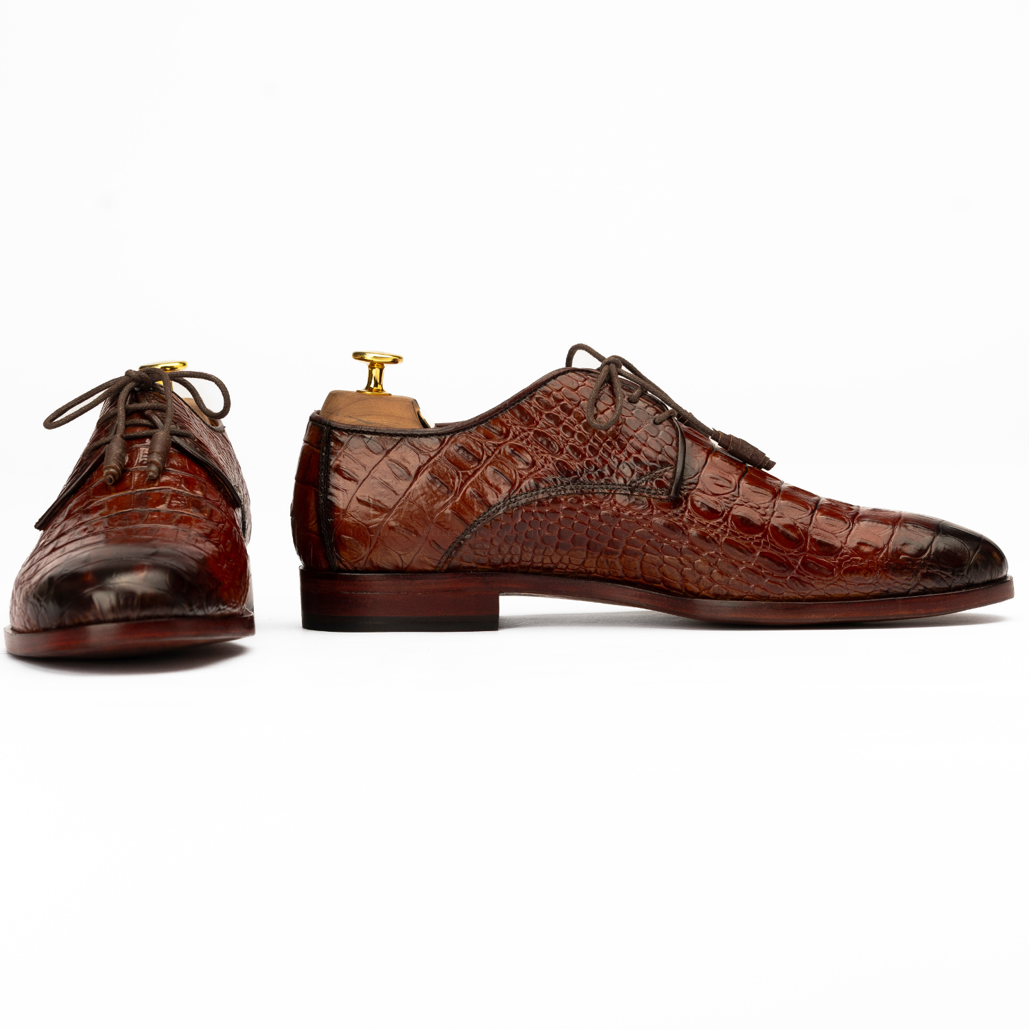 Brown crocodile-patterned dress shoes on a white background