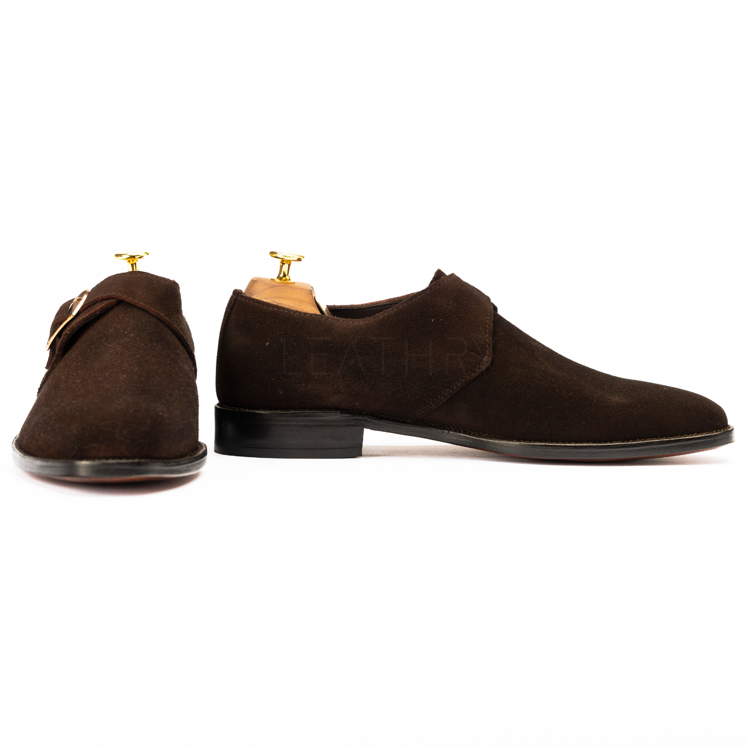 Brown suede shoes with gold buckles on a white background