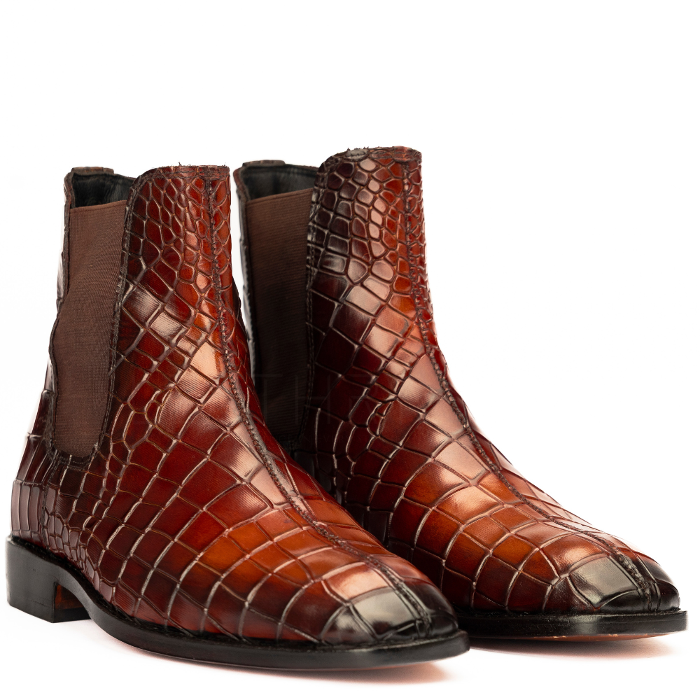 Brown crocodile-patterned leather boots on a white background