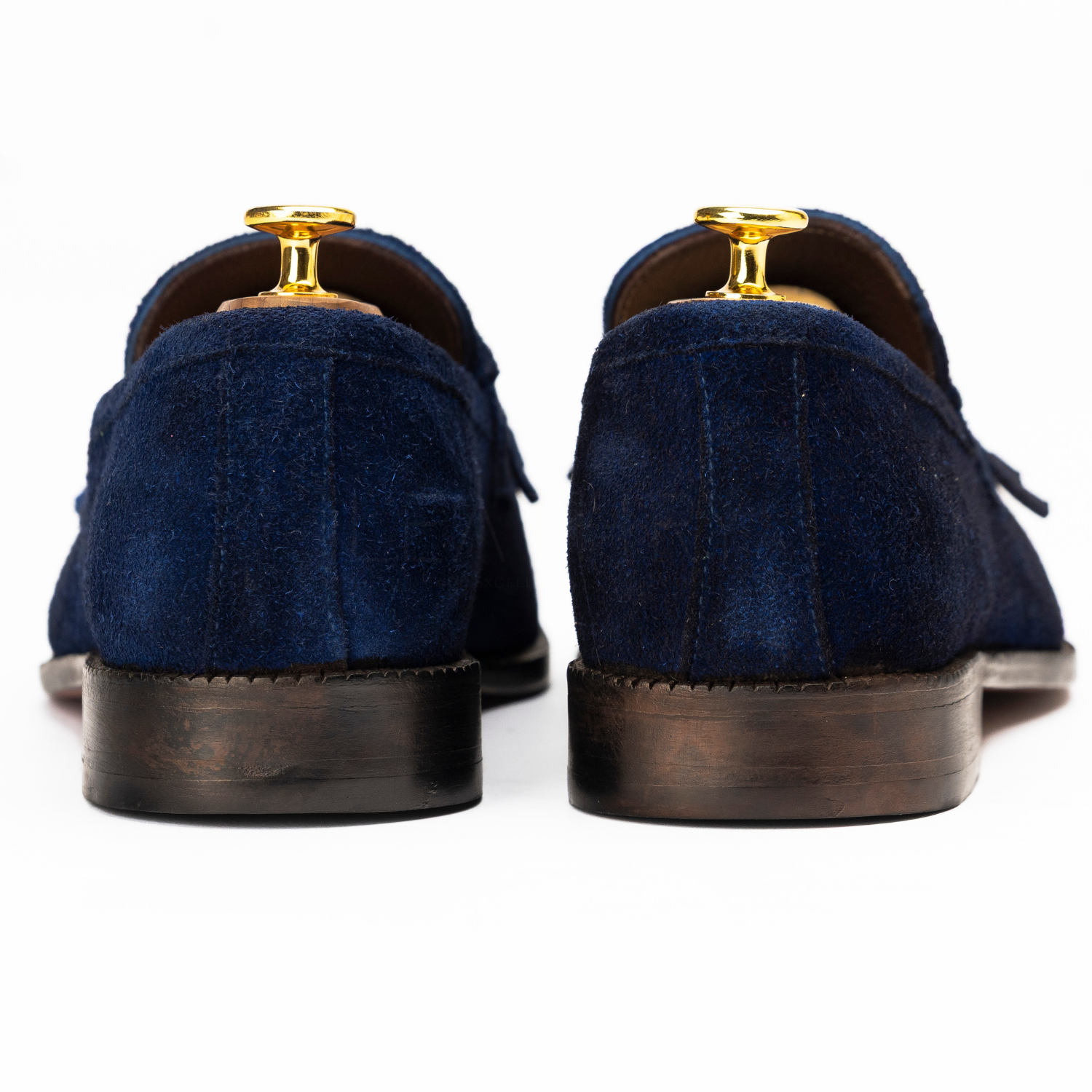 Pair of navy blue suede shoes with gold dress studs on a white background