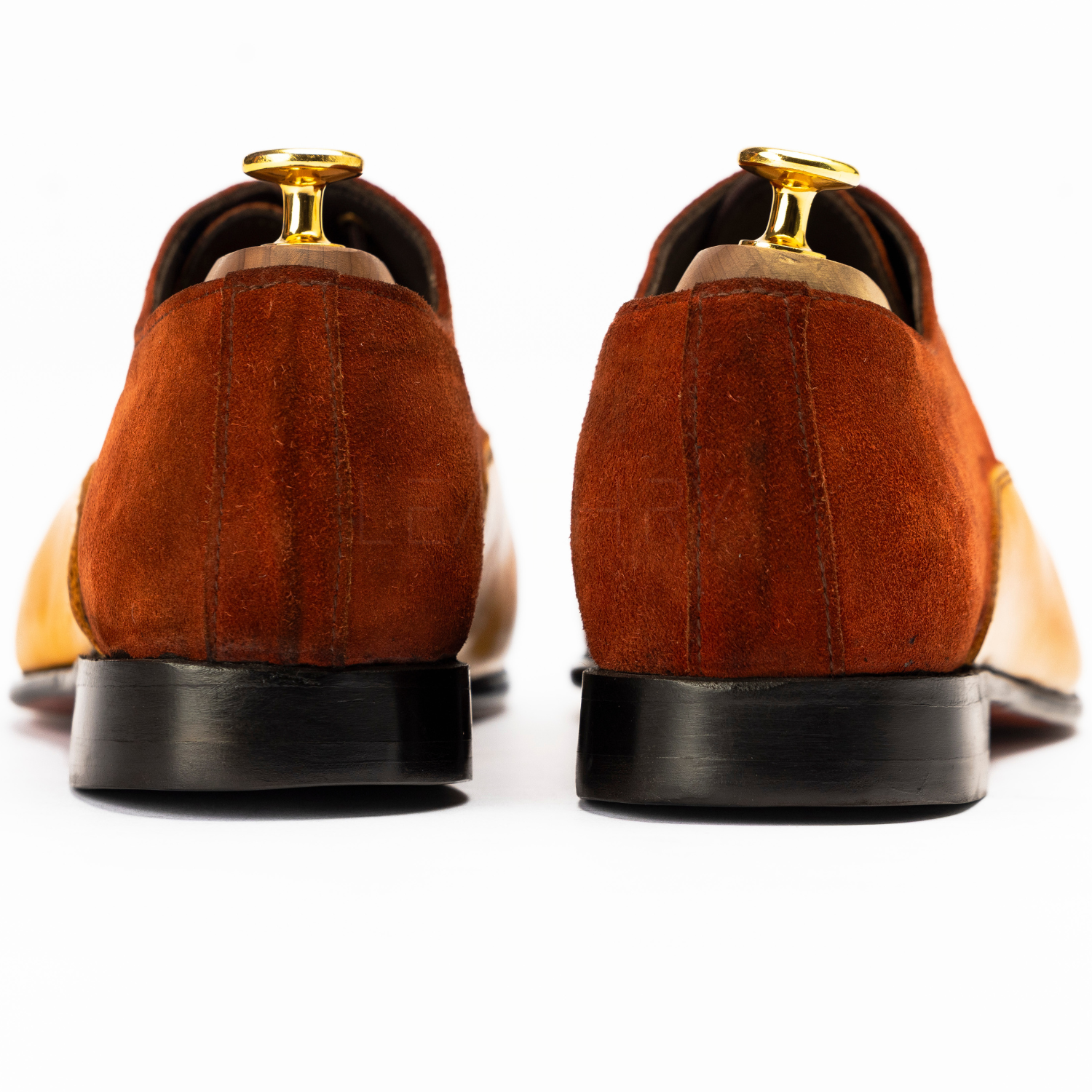 Brown suede shoes with gold accents on a white background