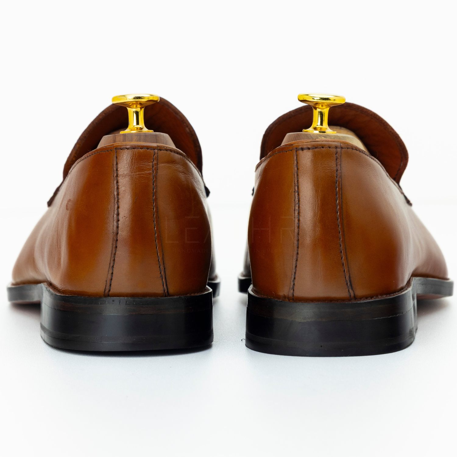 Brown leather shoes with gold accents on a white background