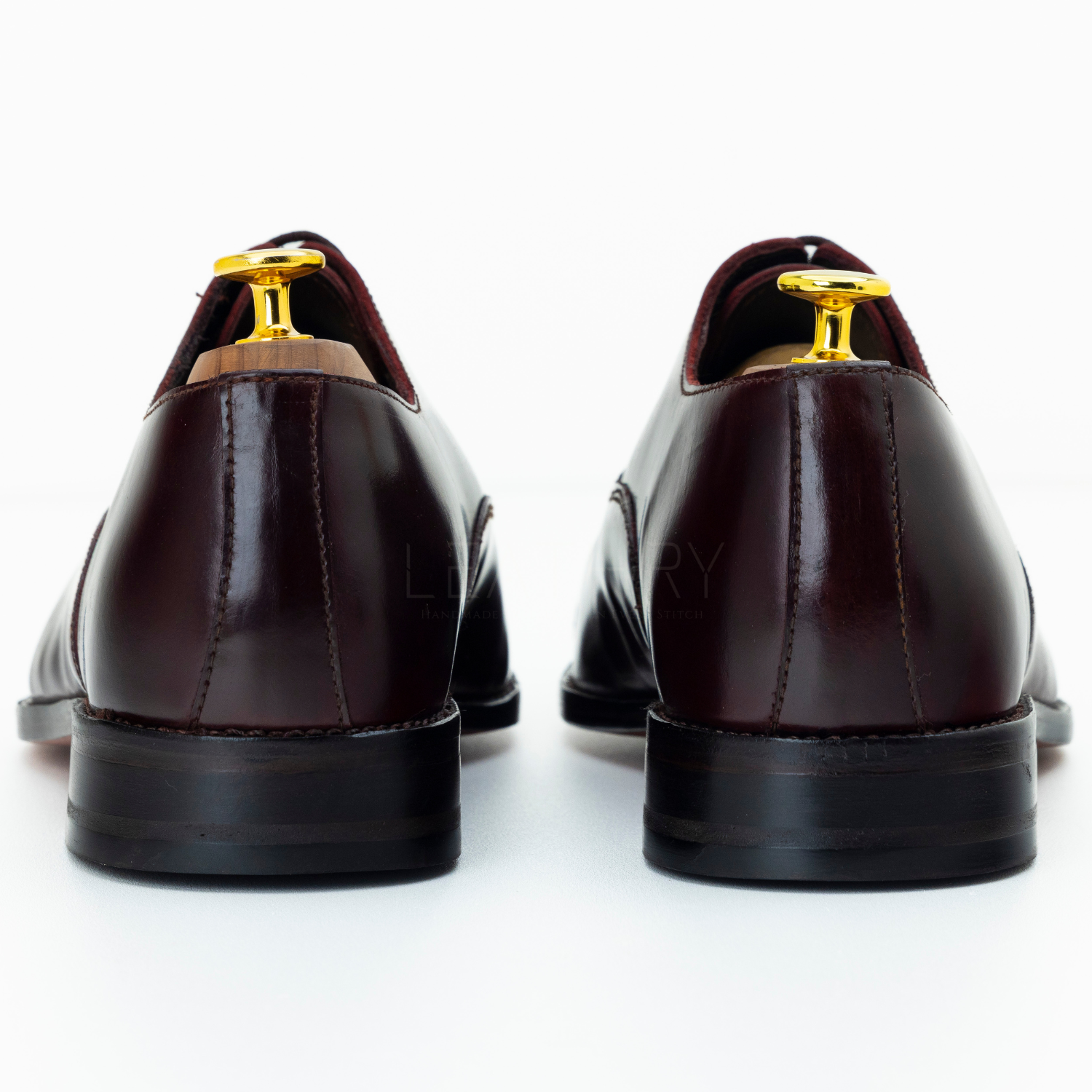 Pair of brown dress shoes with gold accents on a white background