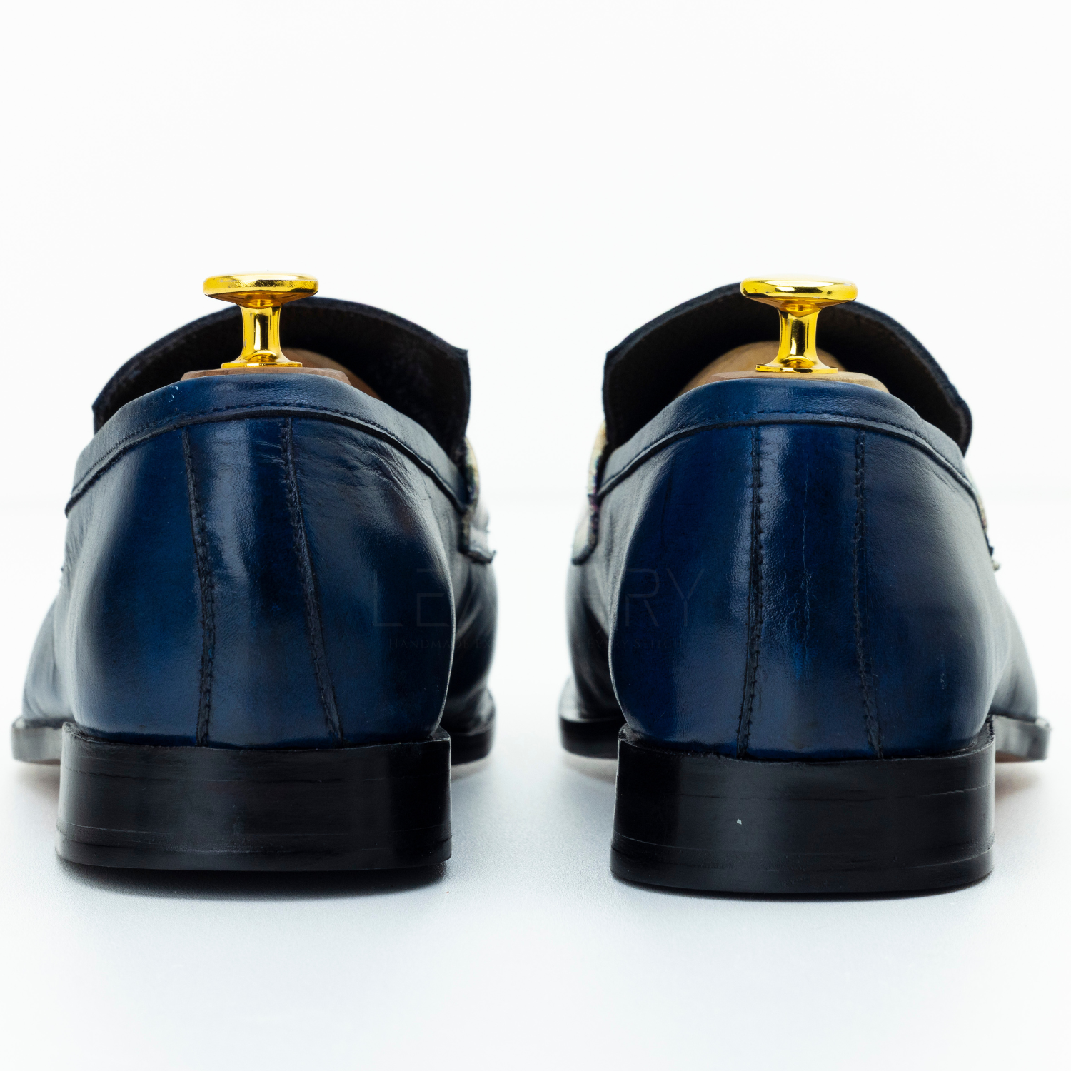 Pair of blue leather shoes with gold buckles on a white background