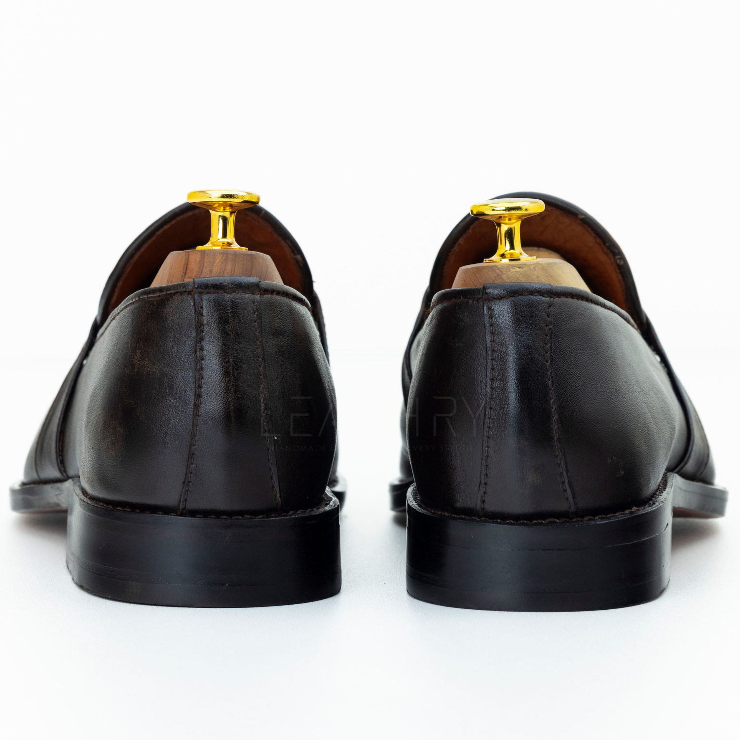 Black leather shoes with gold buckles on a white background
