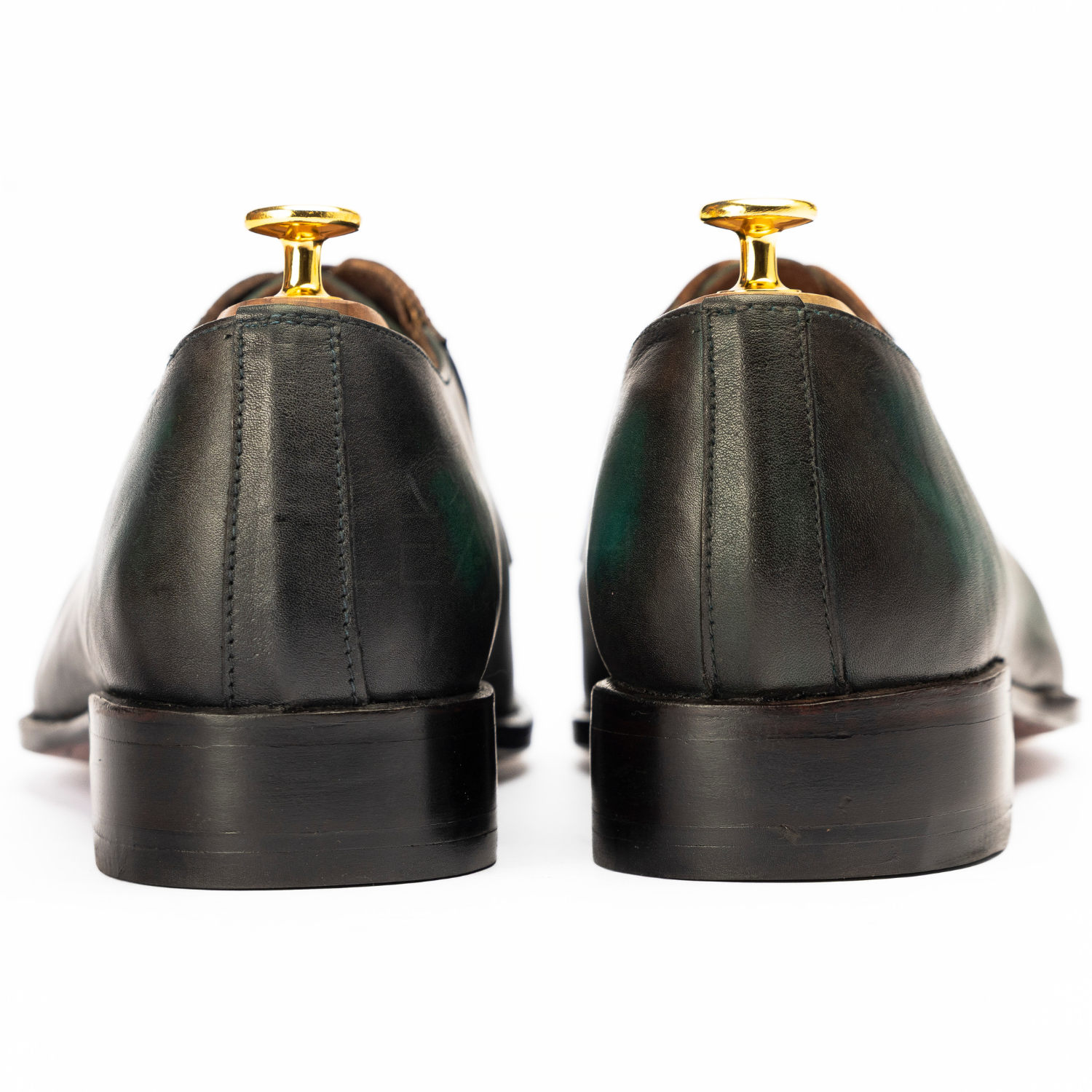 Black leather dress shoes with gold tips on a white background