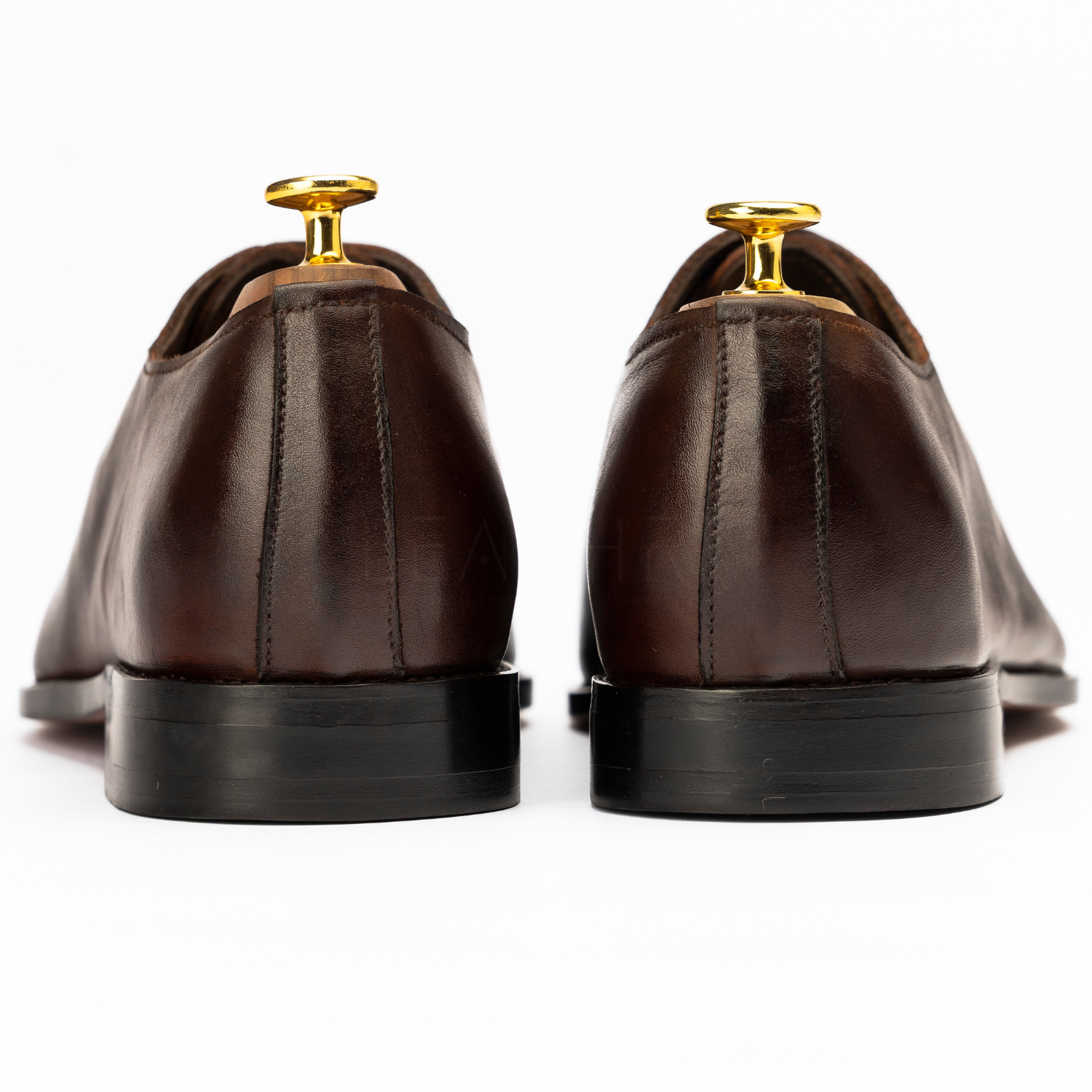 Pair of brown leather shoes with gold dress studs on a white background