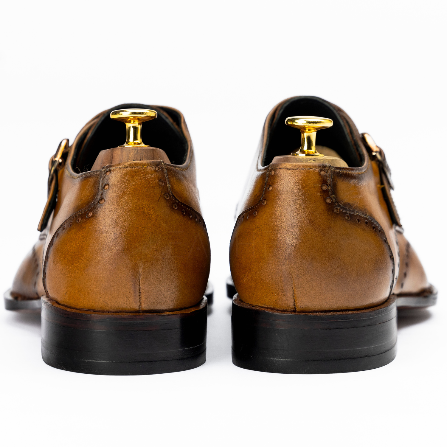 Brown leather shoes with gold buckles on a white background