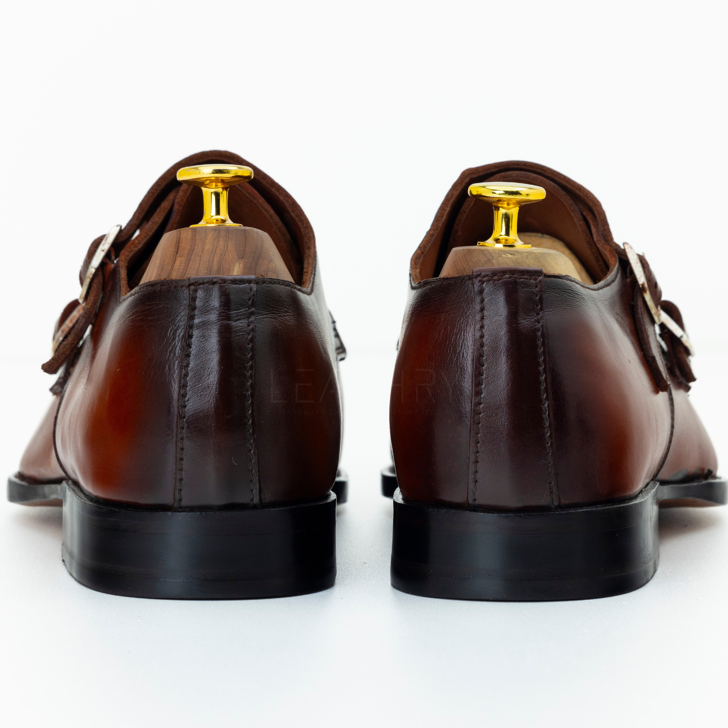 Brown leather shoes with gold buckles on a white background