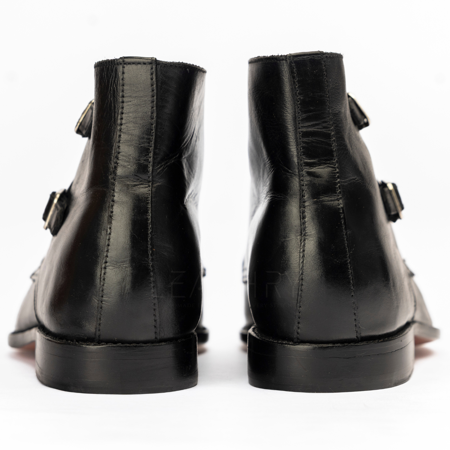 Black leather boots with buckle details on a white background