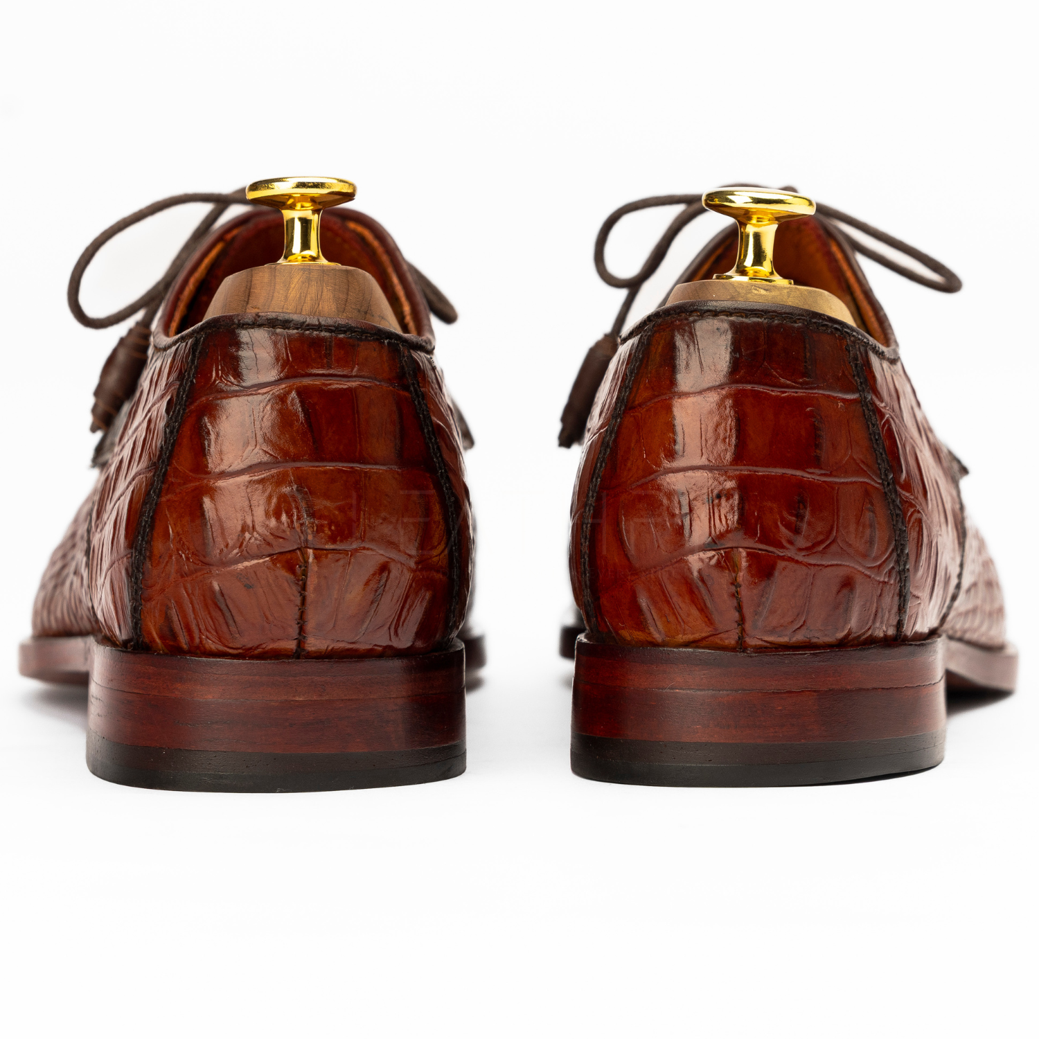 Brown leather shoes with gold accents on a white background