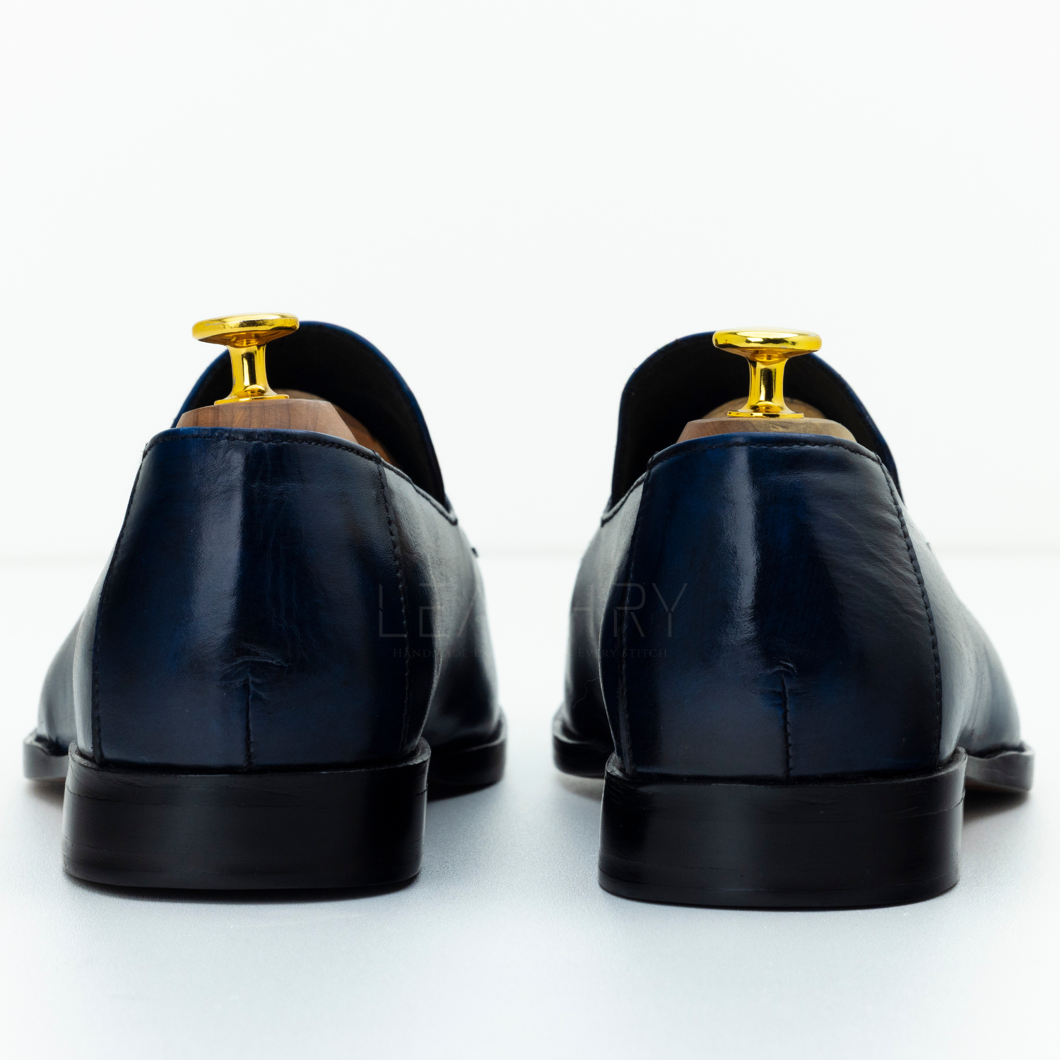Black leather shoes with gold accents on a white background