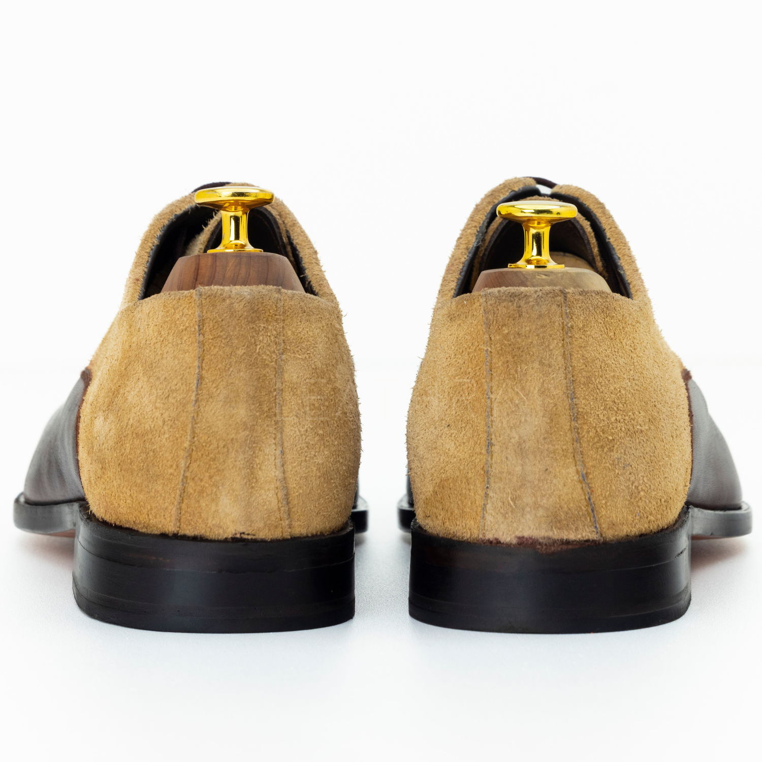 Pair of brown suede shoes with black soles on a white background