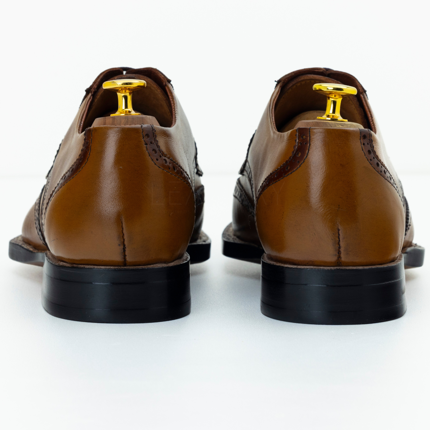 Brown leather dress shoes with gold dress studs on a white background