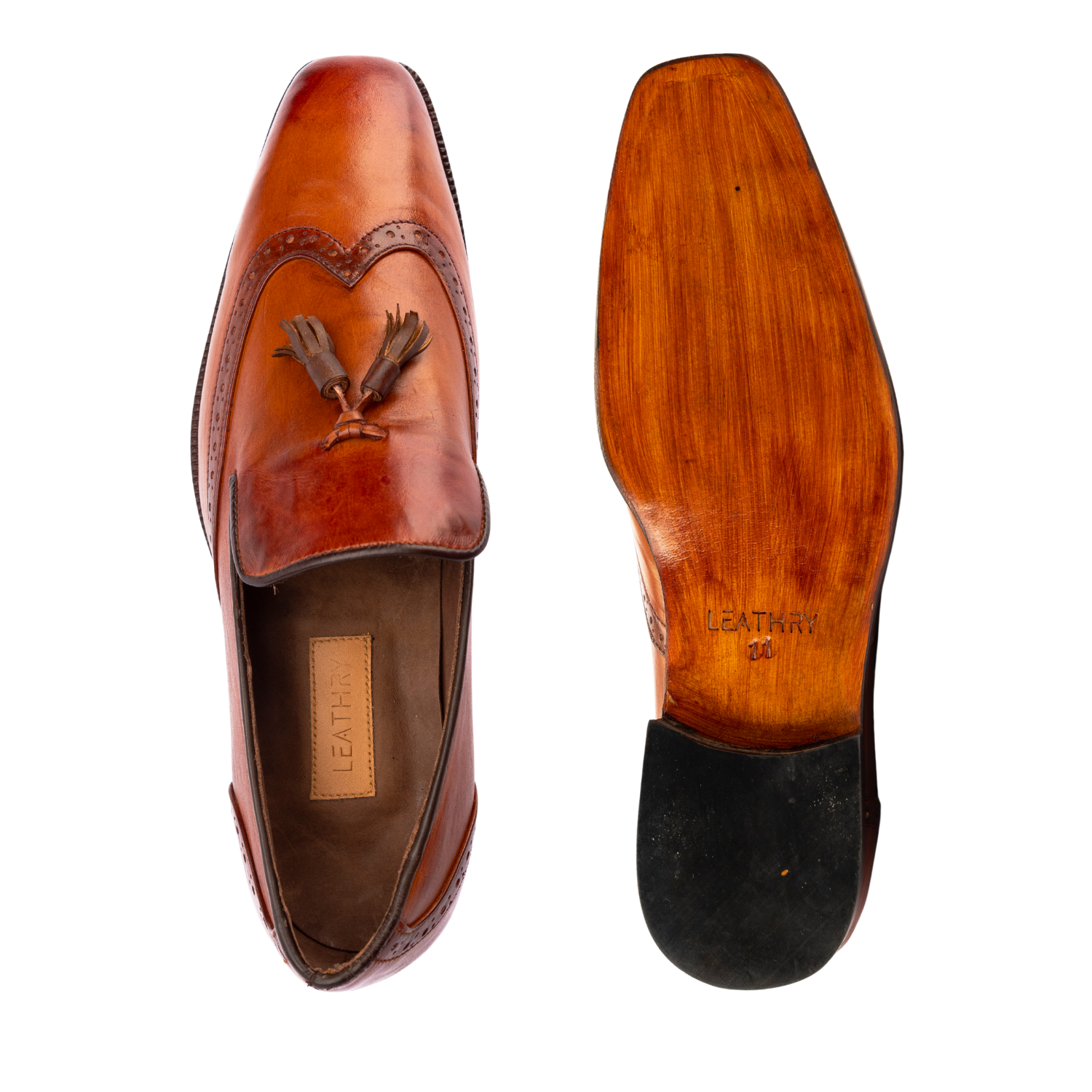 Brown leather loafer with decorative emblem on a white background