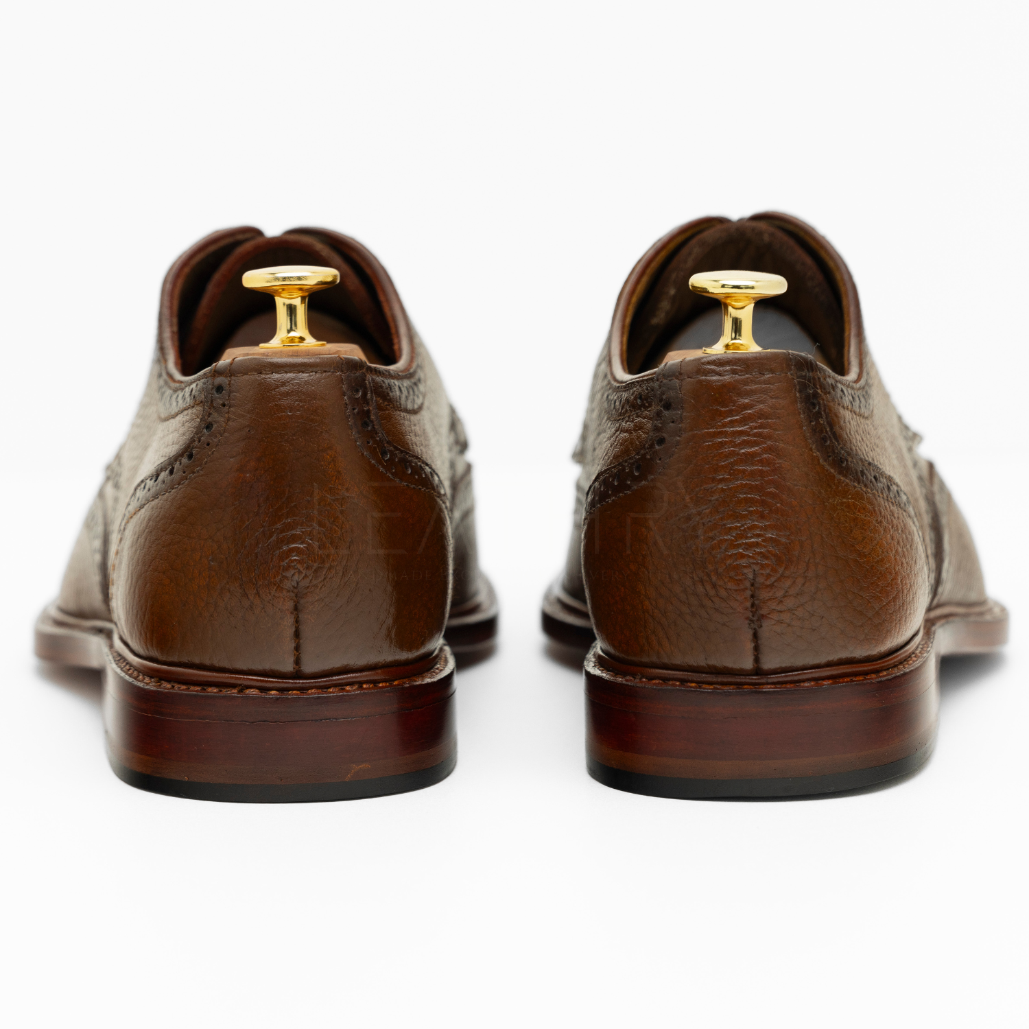 Brown leather shoes with gold buttons on a white background