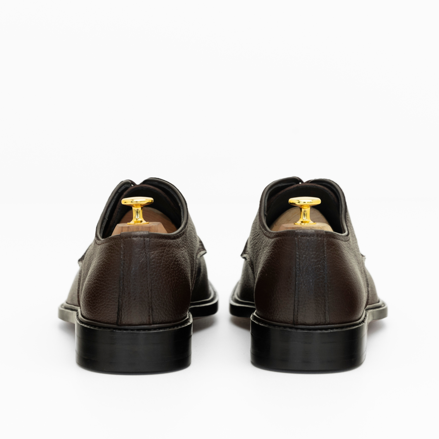 Brown leather shoes with gold buttons on a white background