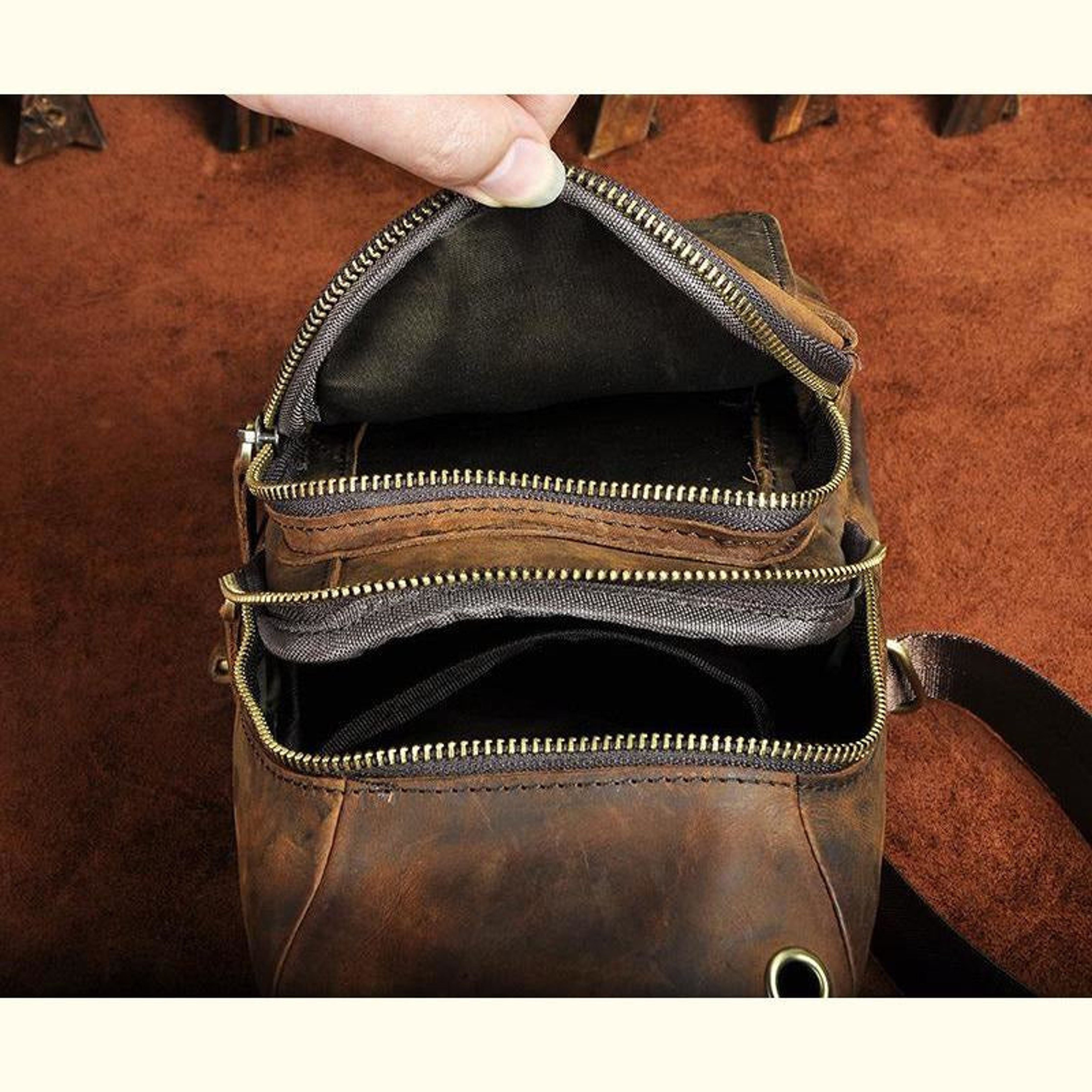 Brown leather bag with gold zipper being opened on a brown background