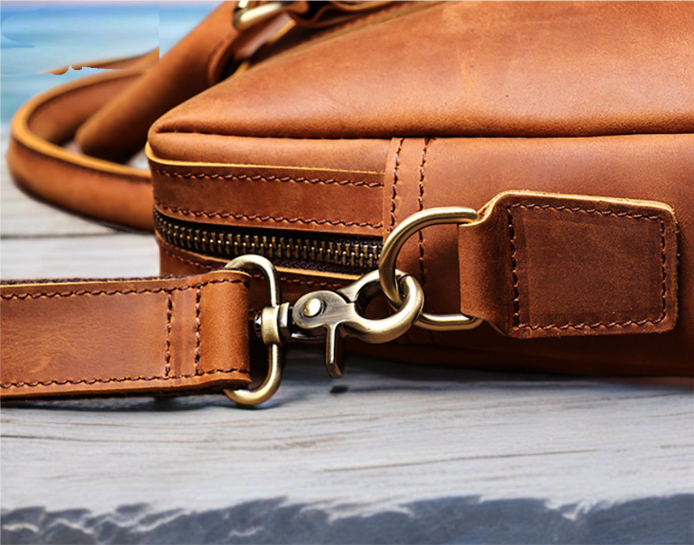Brown leather bag with gold zipper pull on a wooden surface