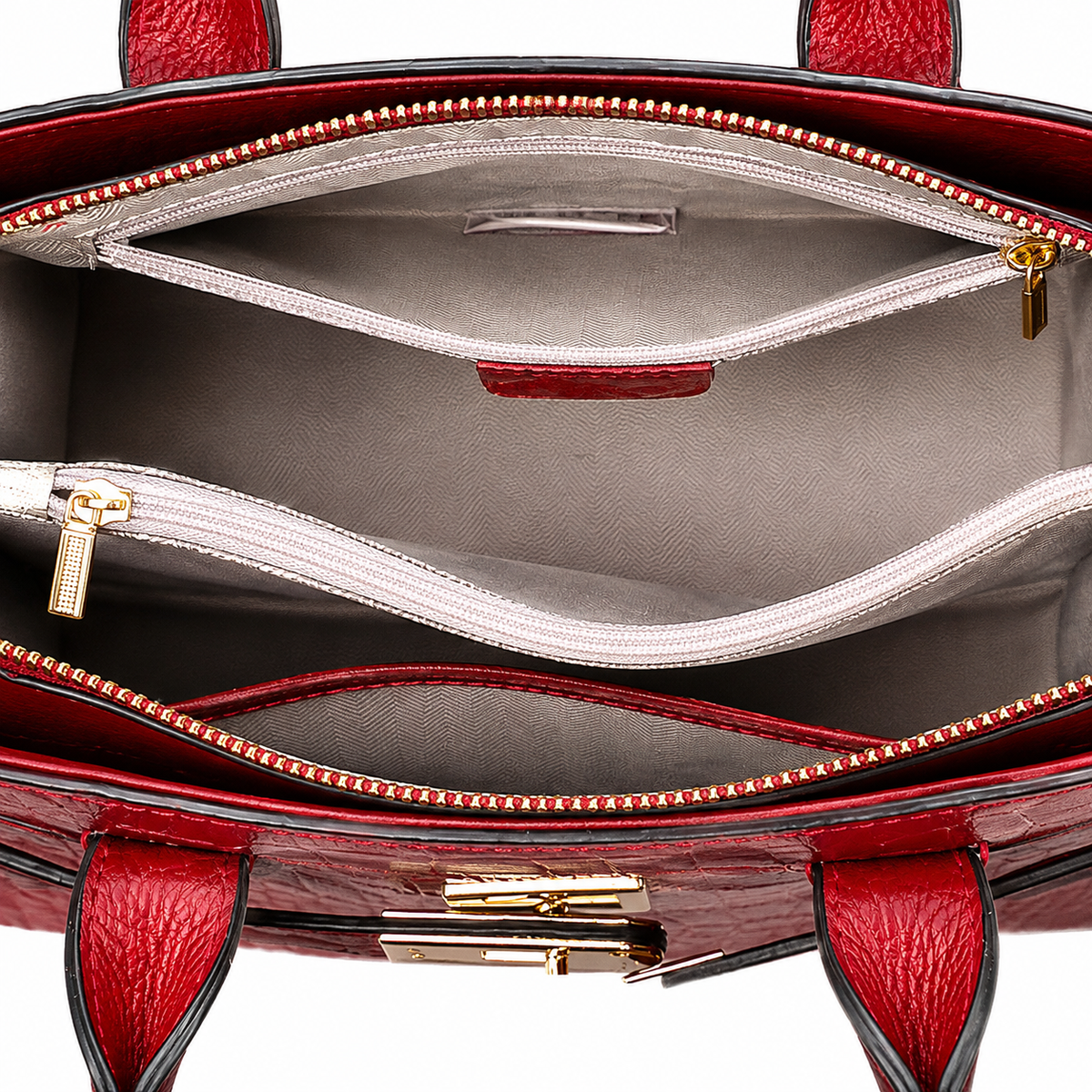 Close-up of the interior of a red textured leather handbag, showing two zippered compartments with light gray lining and gold-tone hardware.