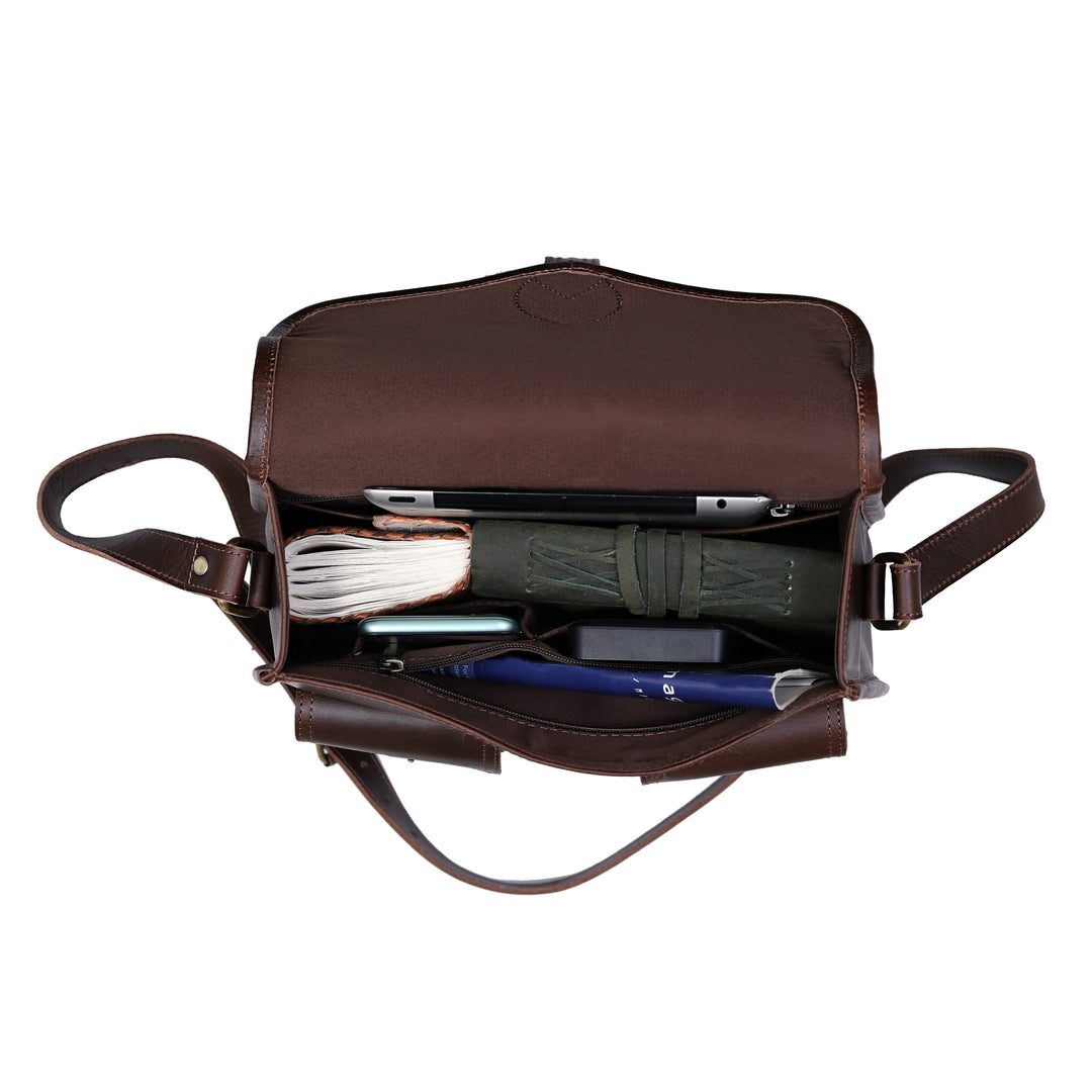 Brown leather bag with compartments and items on a white background