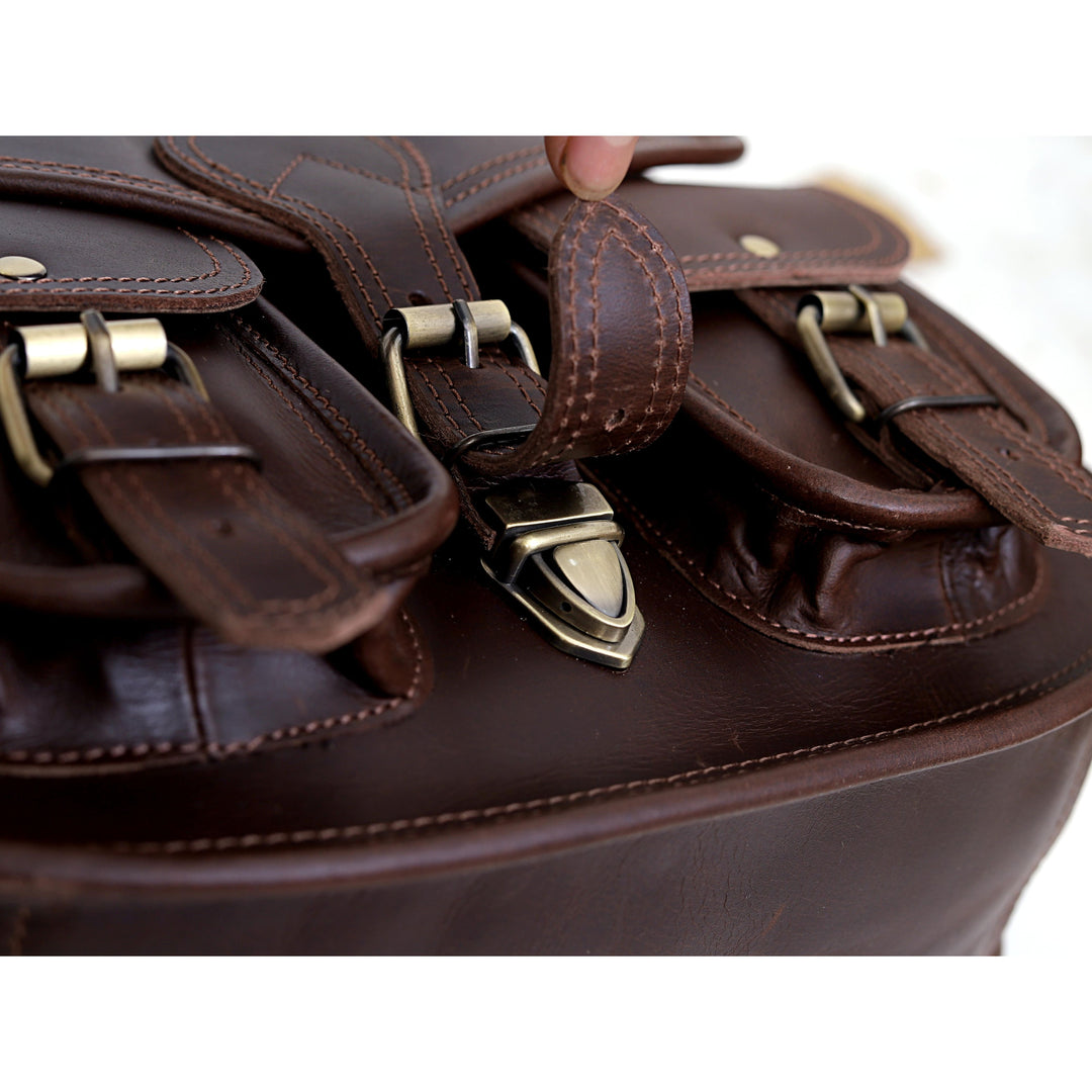 Close-up of a brown leather bag with metal buckles on a white background
