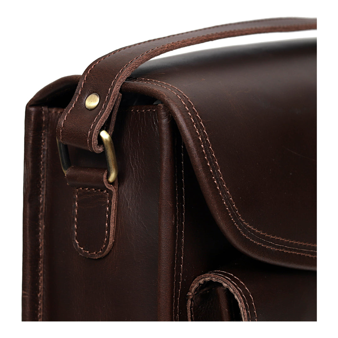 Close-up of a brown leather bag with a strap and buckle on a white background