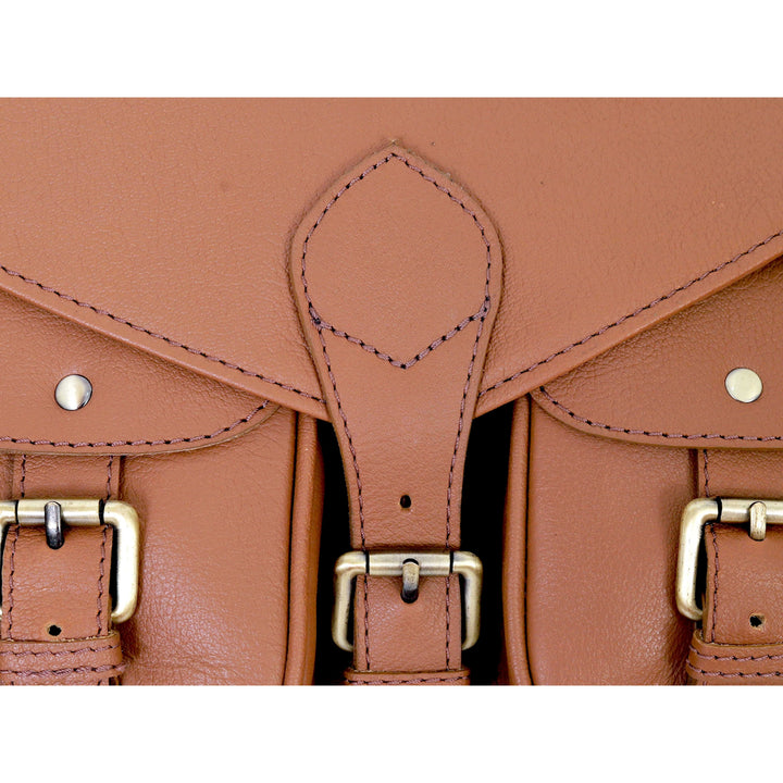 Close-up of a brown leather satchel with gold buckles on a white background