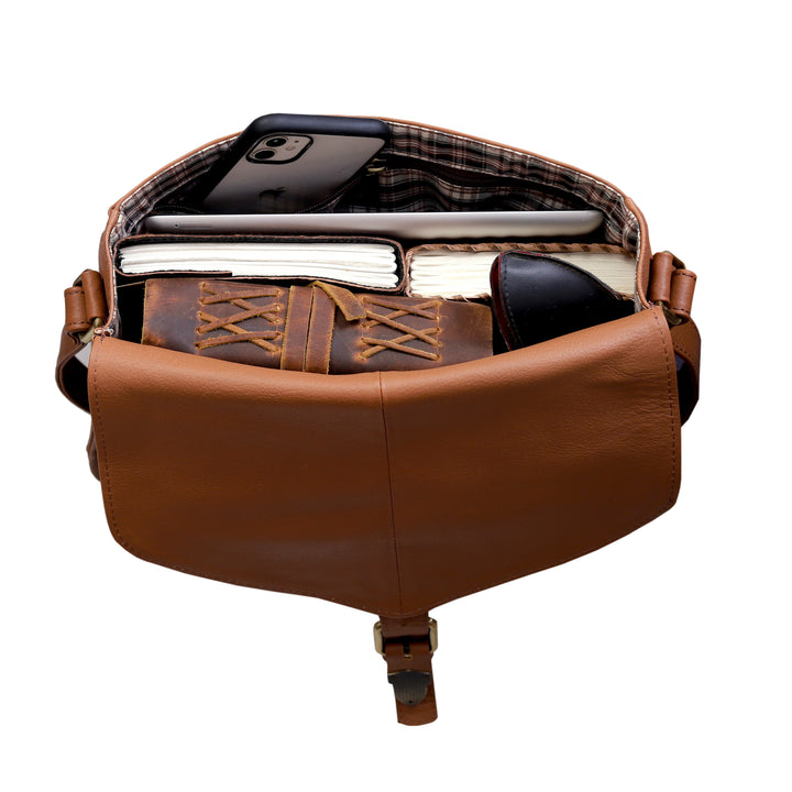 Brown leather bag with compartments containing books and a phone on a white background